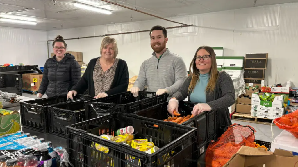 Four members of the Utter Morris team sorting food and smiling at the local food bank