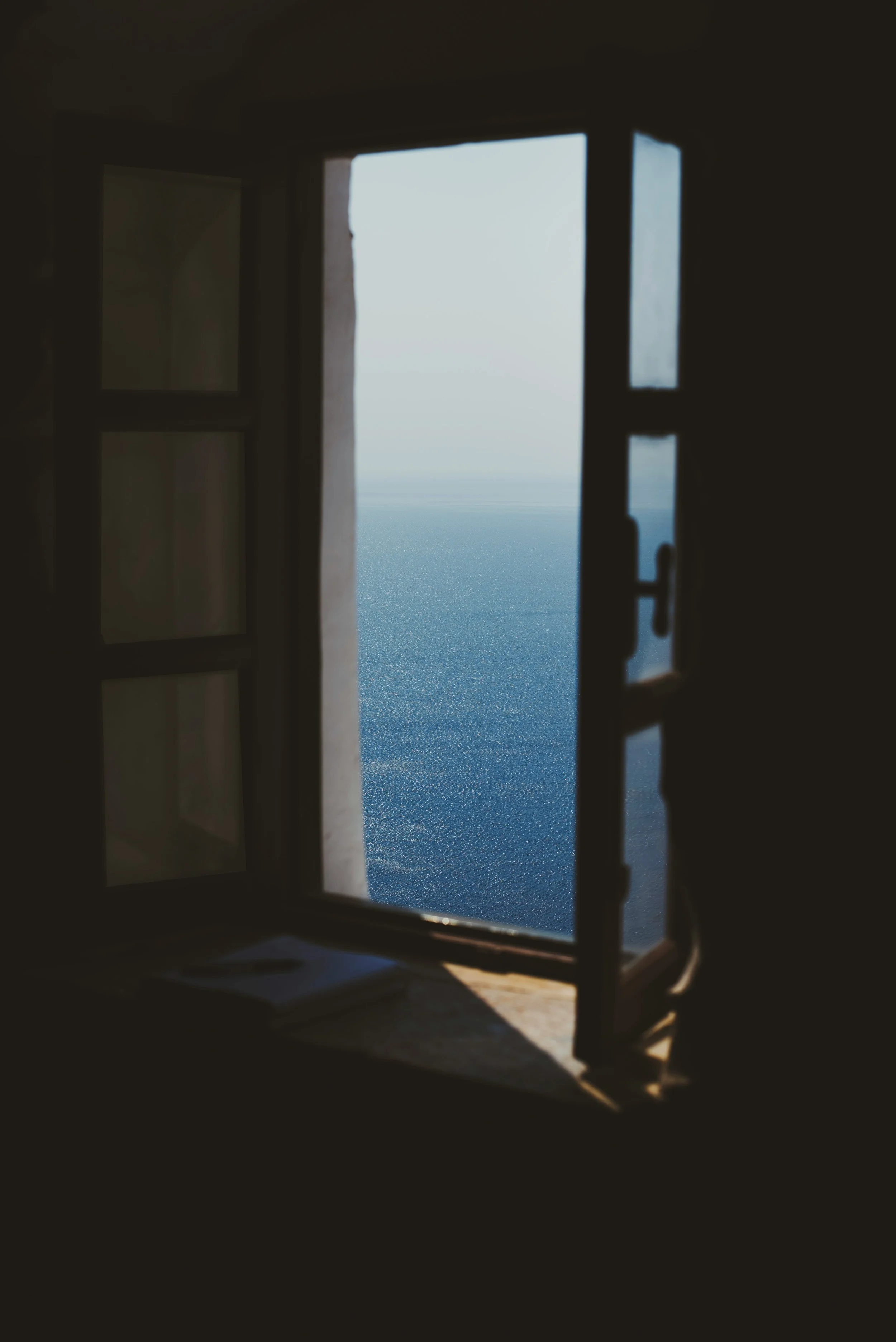 Open window revealing a view of the sea and sky.