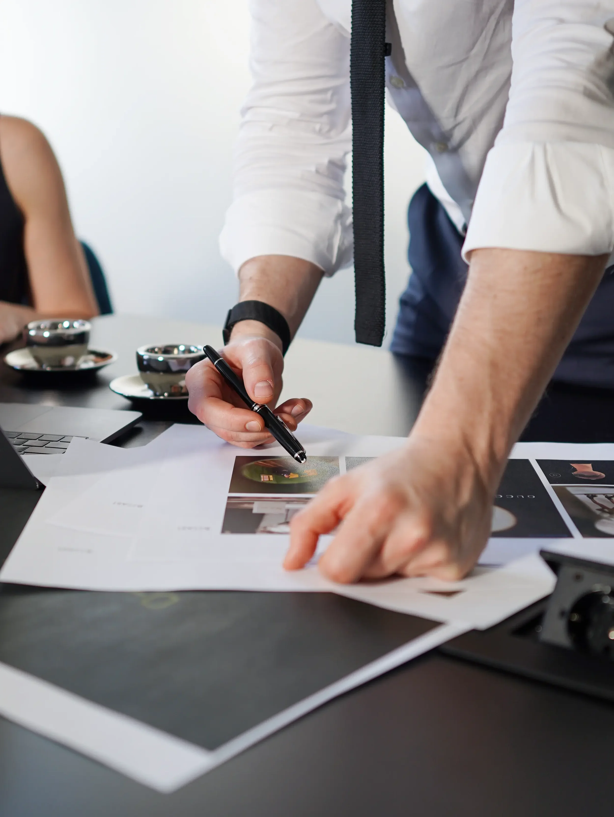 Close-up of man's hands with pen reviewing printed photo selects on dark table, behind the scenes corporate shoot New Moon Agency Klagenfurt