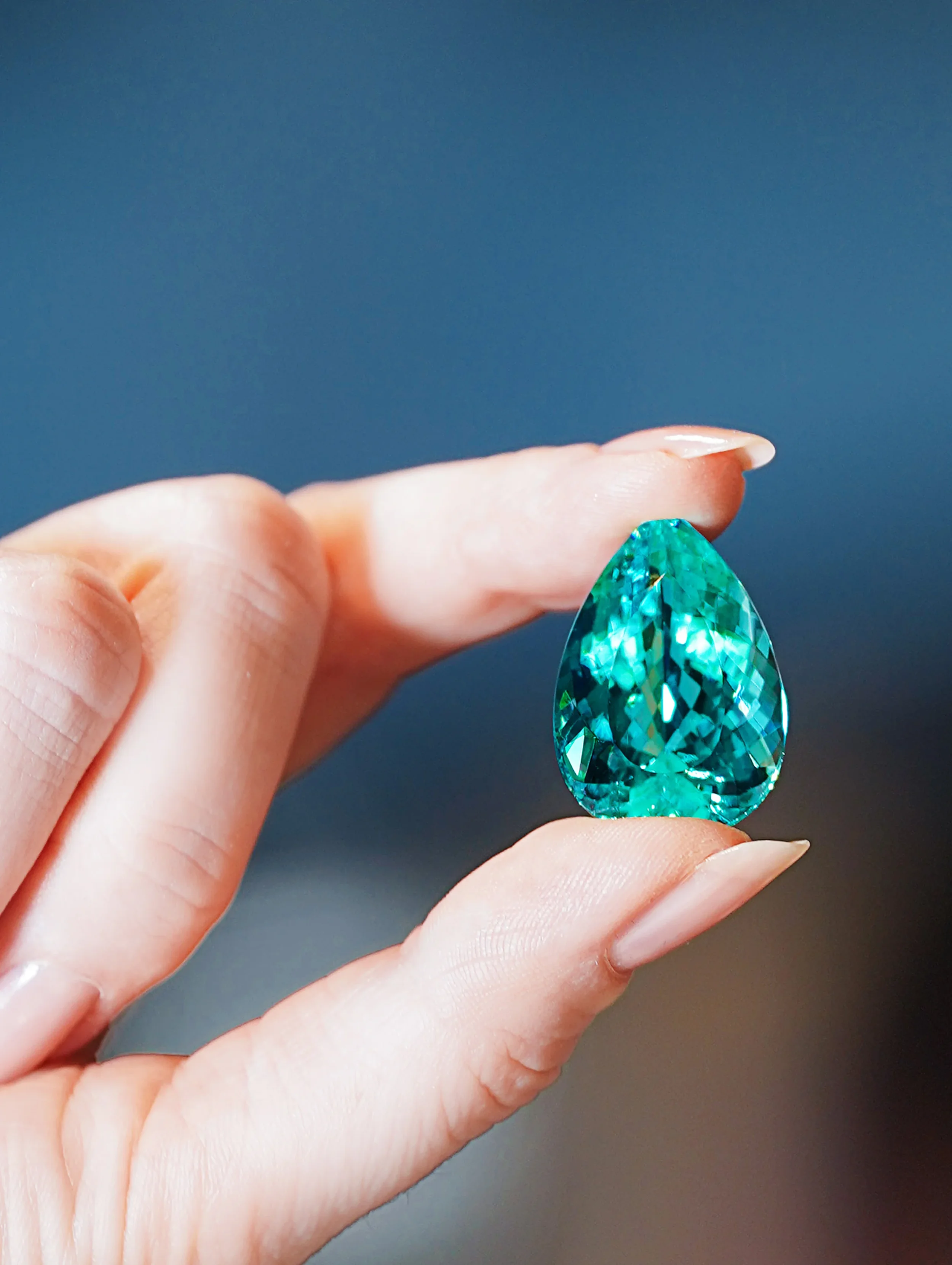 Paraíba tourmaline, roughly 40 carats, held in hand — jewellery photography New Moon Agency