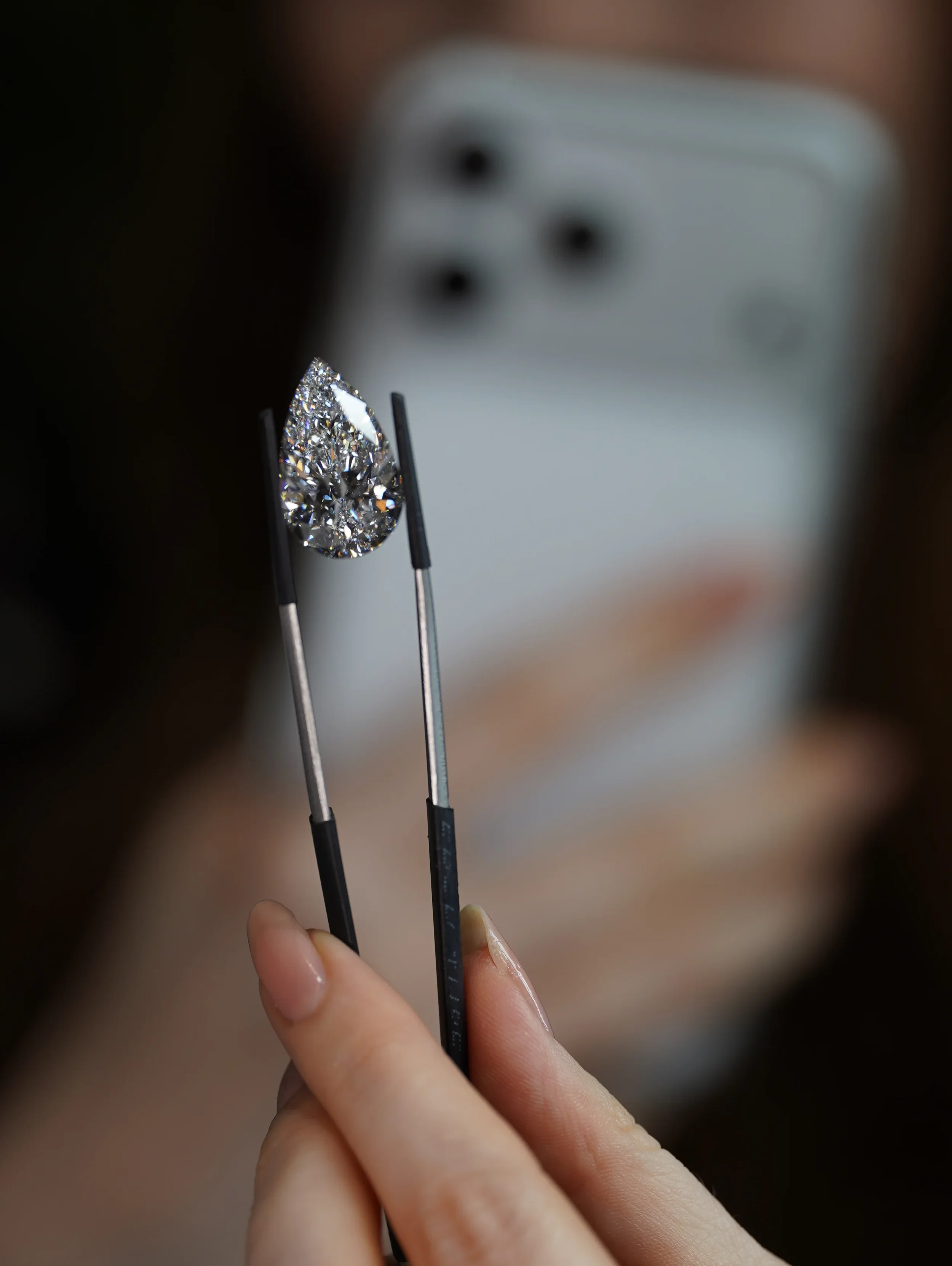 Pear cut diamond held with tweezers macro — jewellery photography New Moon Agency GEM Genève