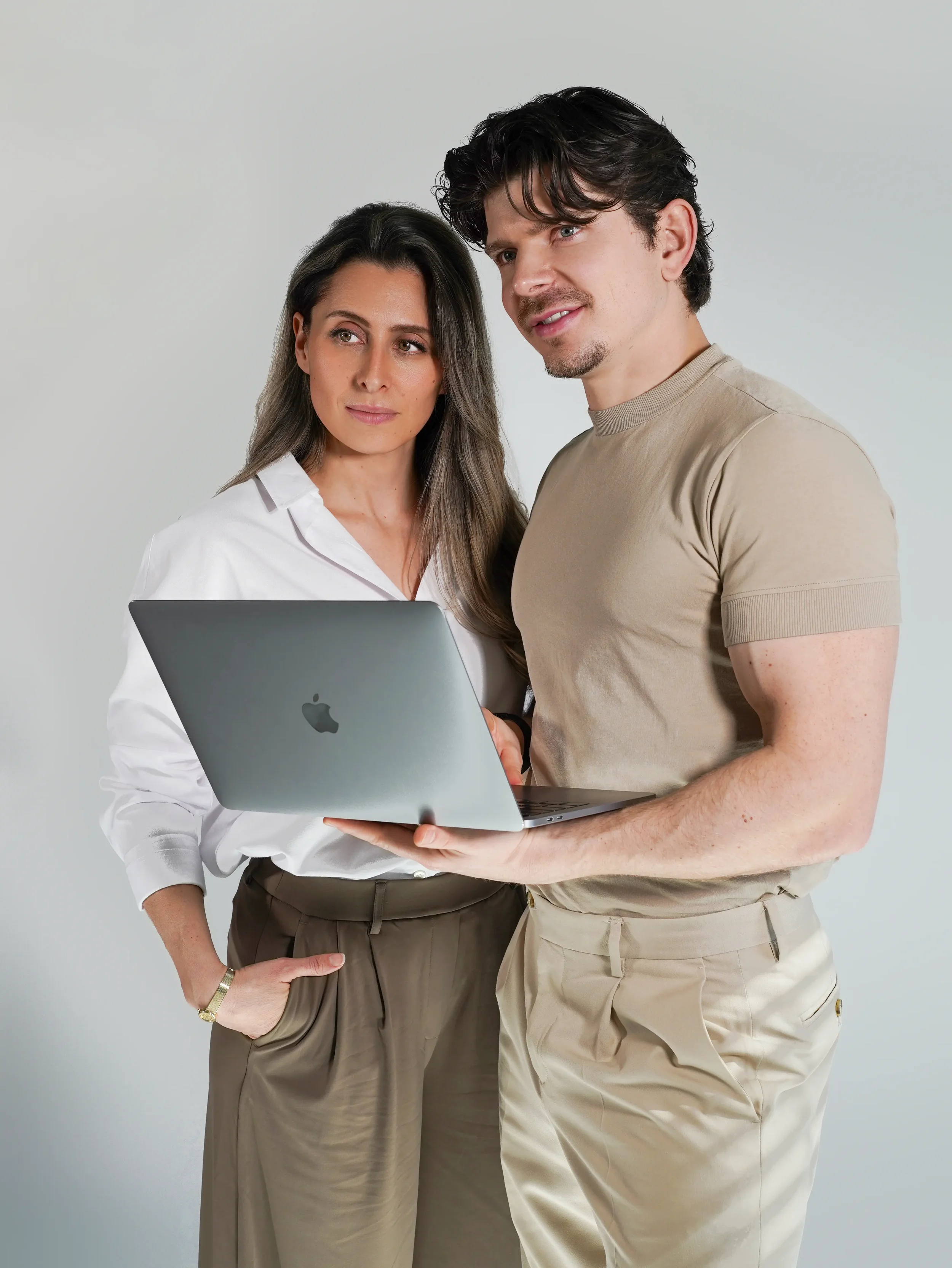 Man and woman standing together holding a laptop, corporate team portrait photography New Moon Agency Klagenfurt
