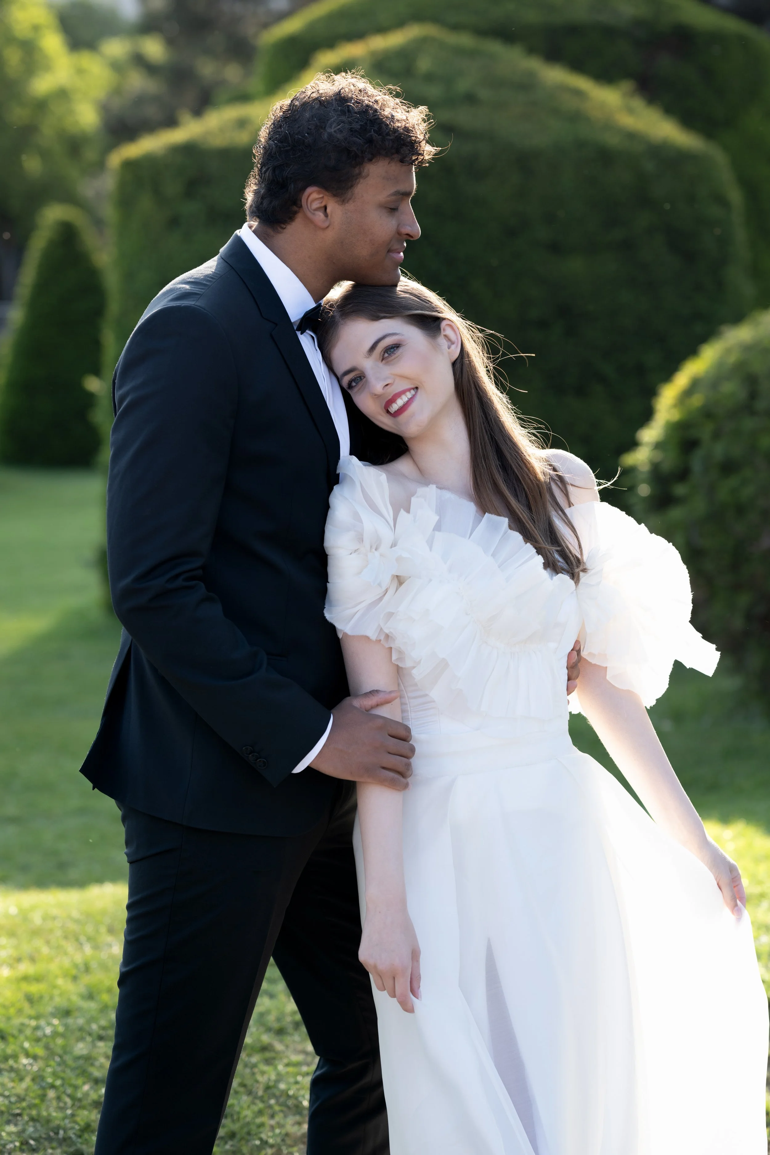 Bride leaning into groom with soft joy – intimate fine art couple portrait.