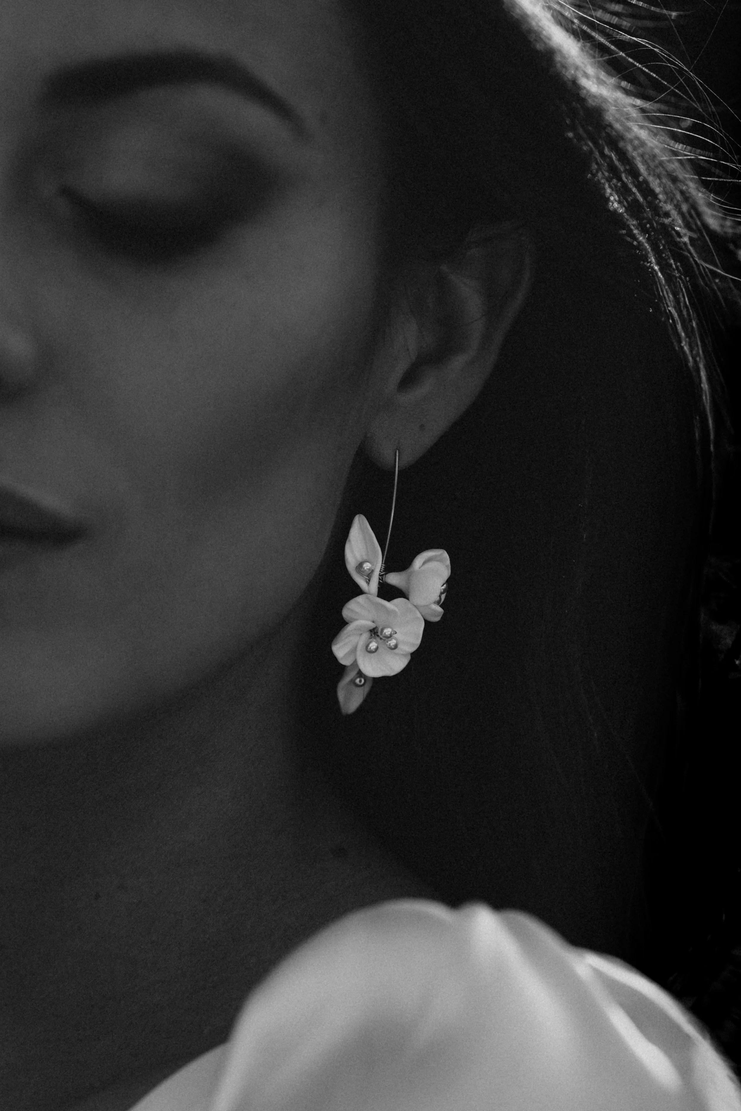Close-up of a floral statement earring on a serene bride in black and white