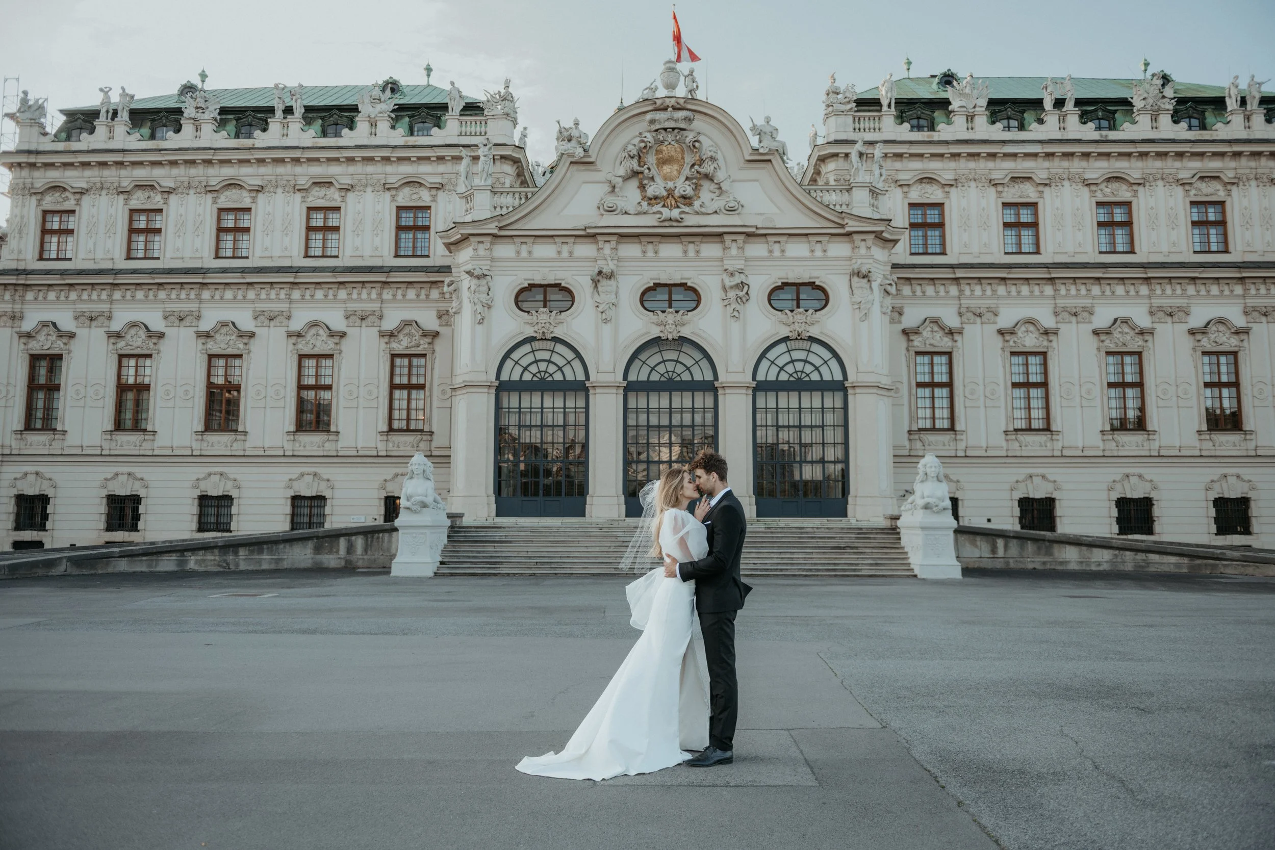 Kiss captured between palace columns – intimate wedding moment in Vienna.