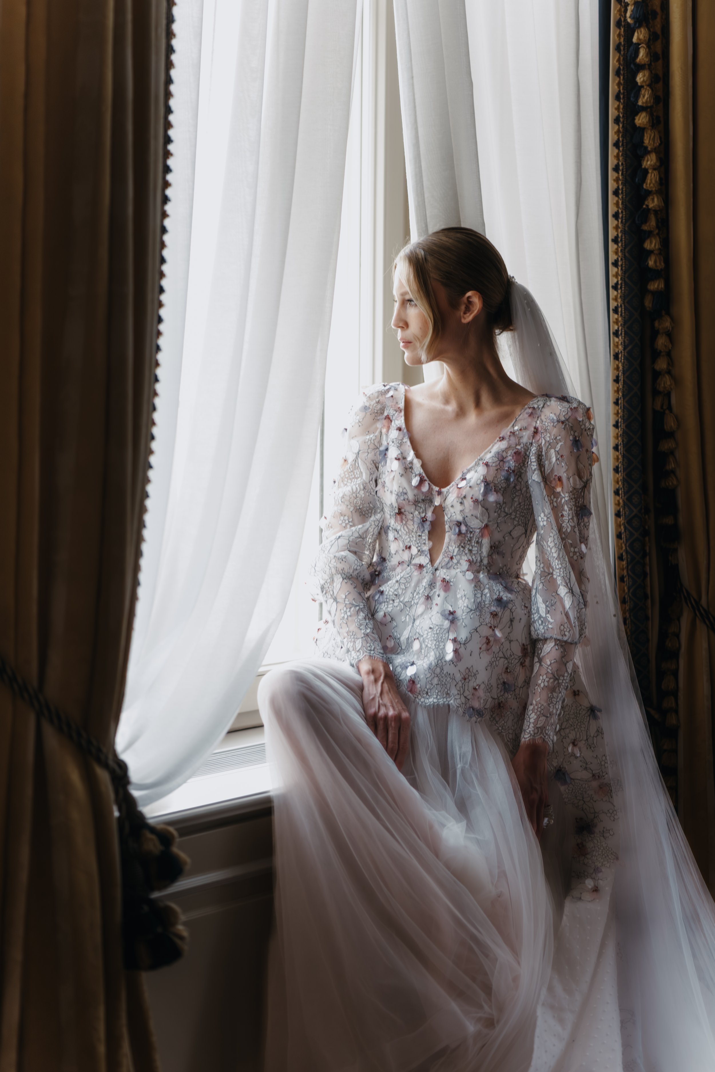 Bride sitting in the window of a castle or hotel room