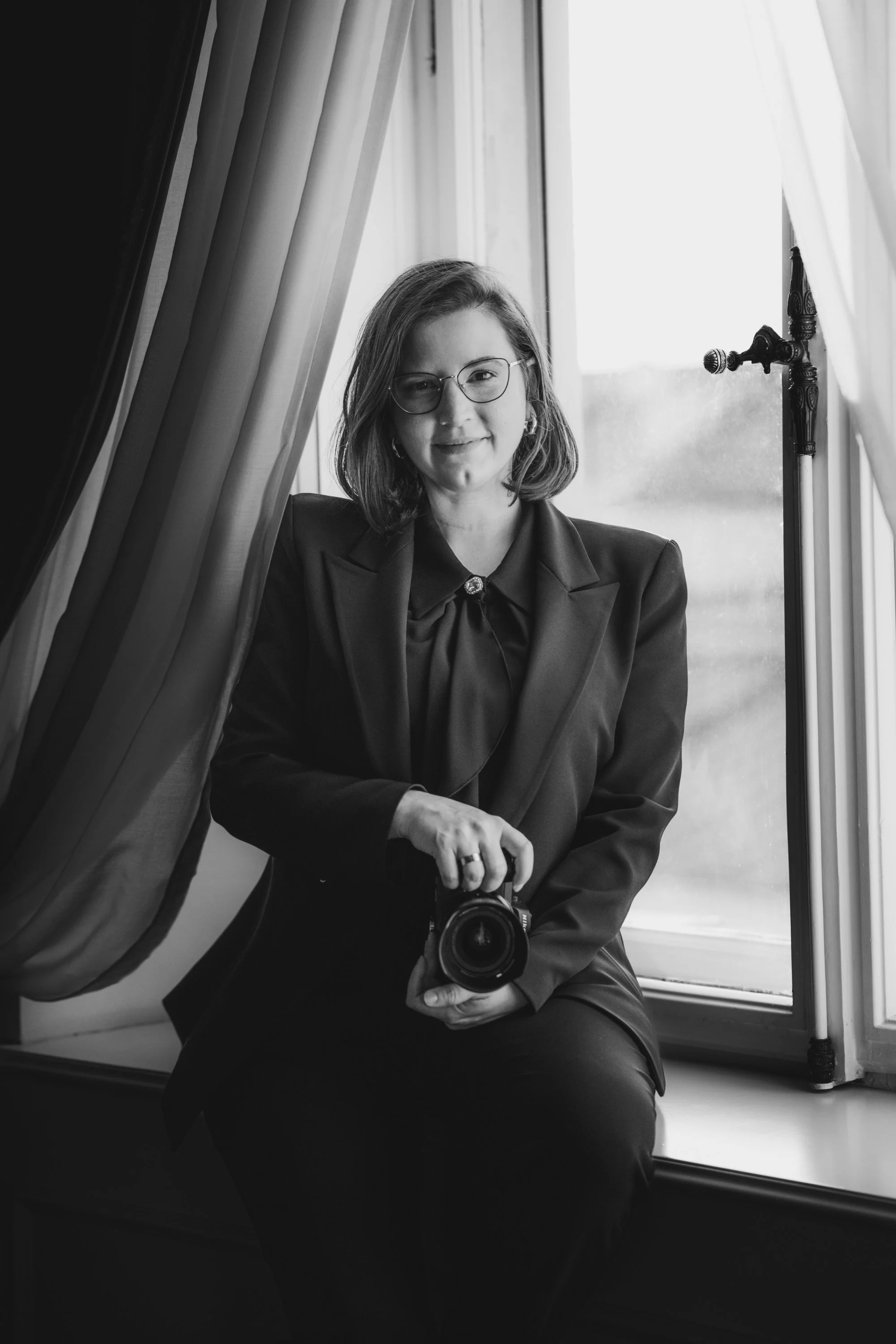 agnes Kinczer photographer sitting in the window with camera