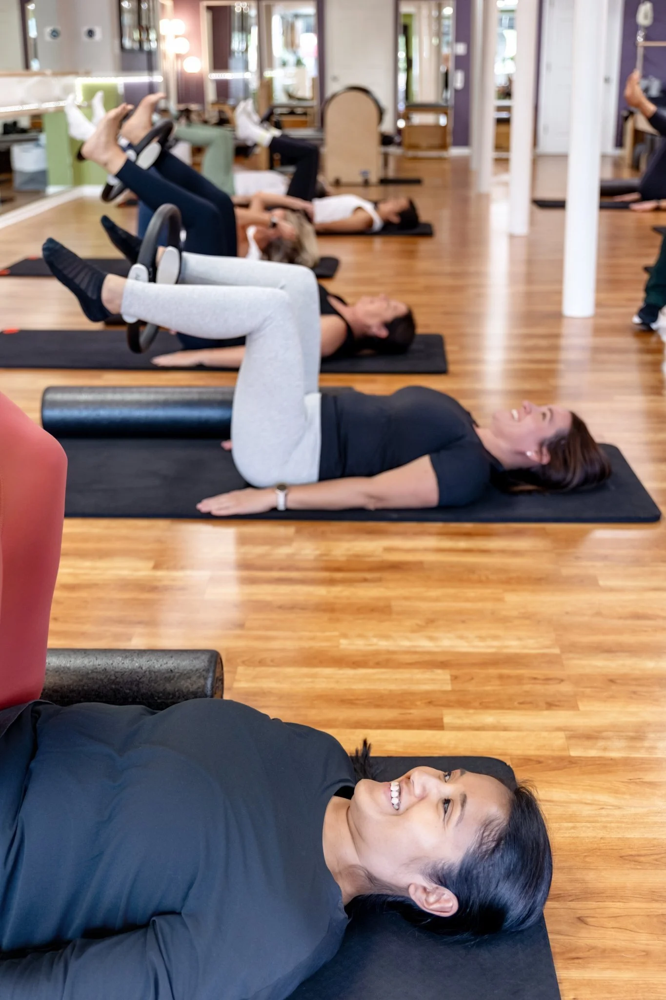 A group of women participating in a fitness class at MBS Pilates, supervised by an instructor.