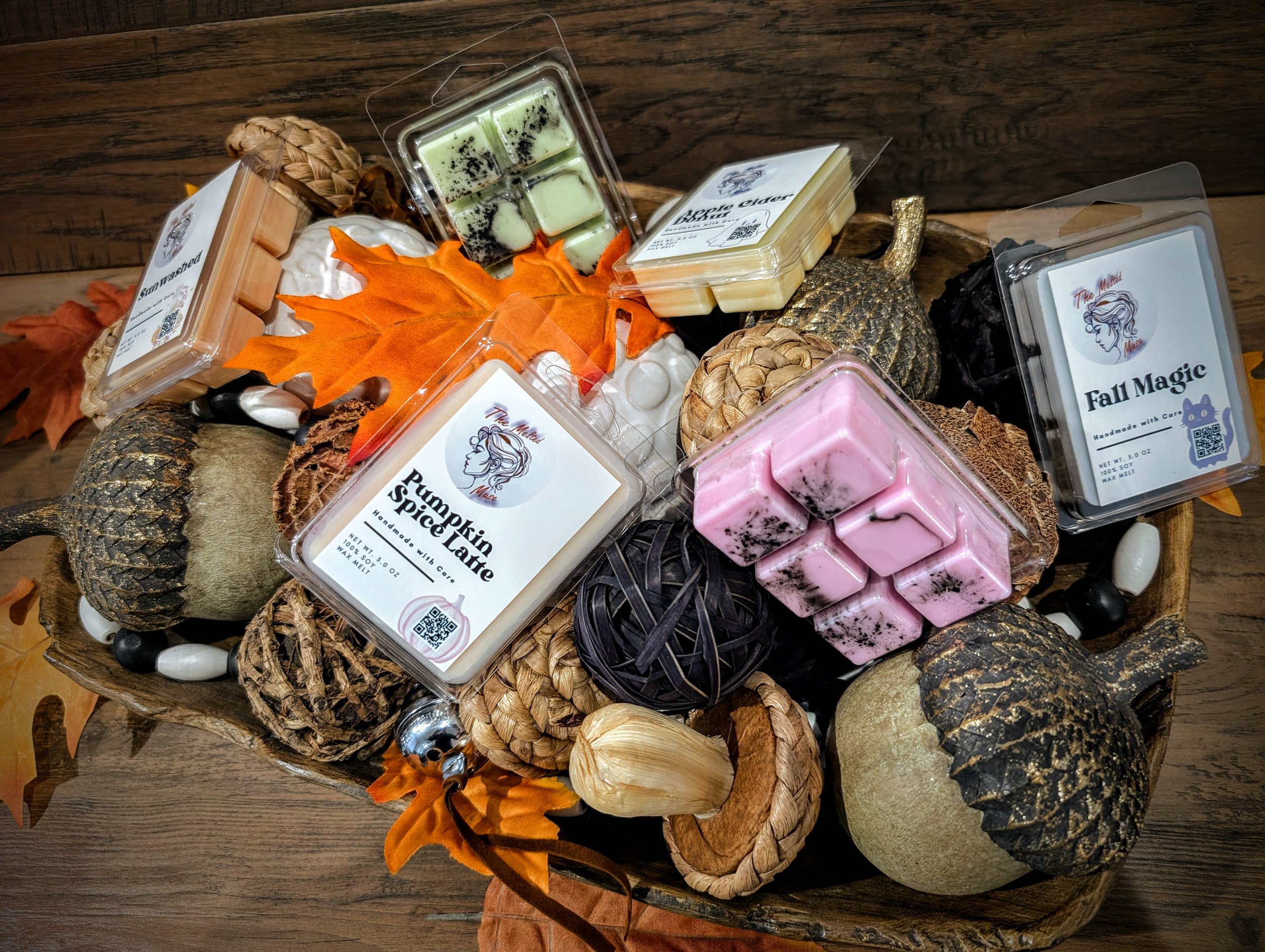Autumn-themed basket filled with candles, pinecones, artificial pumpkins, decorative gourds, wooden beads, and artificial fall leaves.