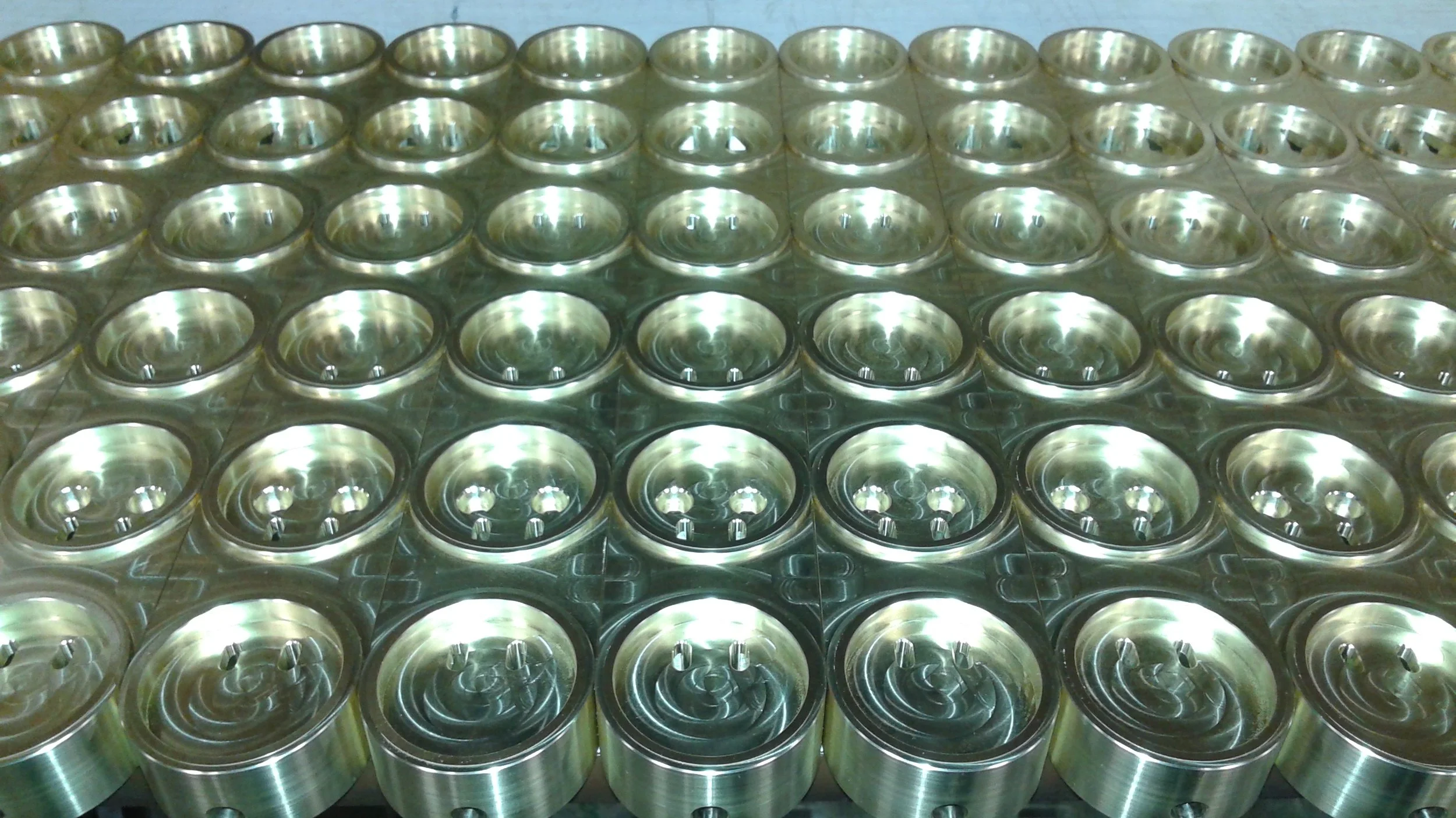 A large number of shiny, metallic, can lids organized in a grid pattern.