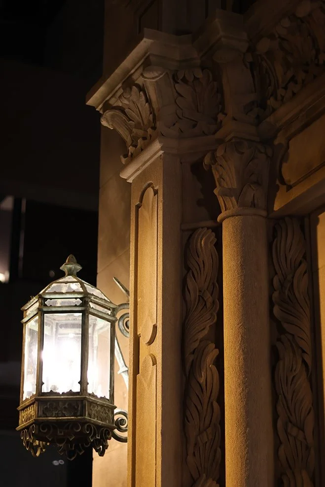 Close-up of an ornate carved wooden structure illuminated by a hanging lantern.