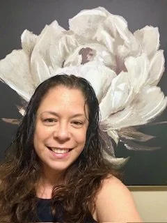 Jami Visaya, Licensed Mental Health Counselor and Marriage and Family Therapist in Bellevue and across WA State standing in front of a flower at Vibrant Life Counseling, LLC in Bellevue, WA.