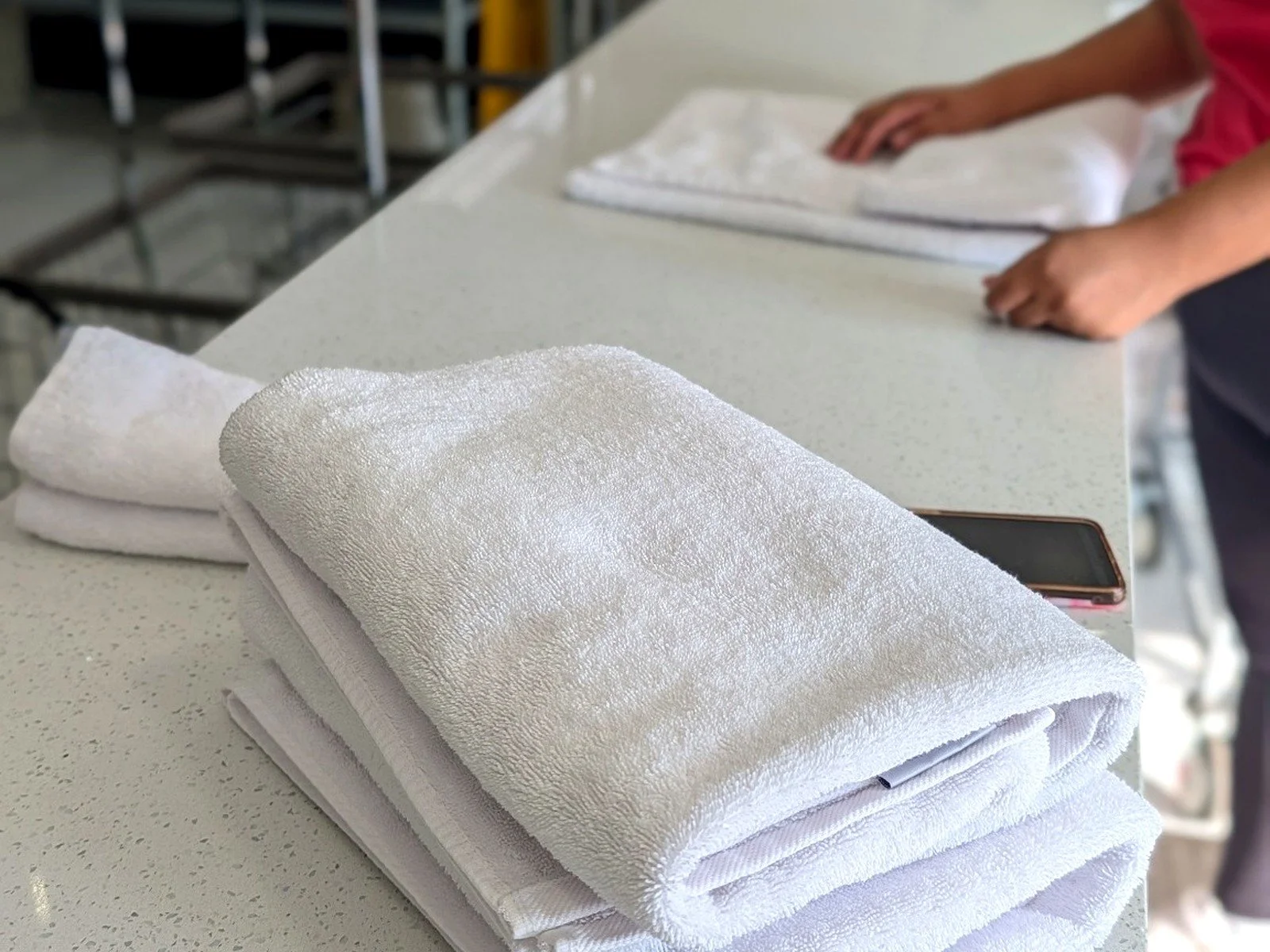 WSHFLD Laundry team member preparing neatly folded white towels at the service counter.
