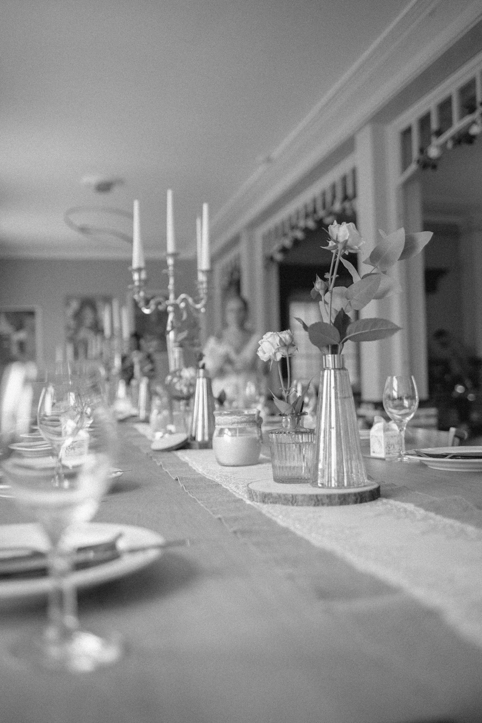 Tischdekoration mit Blumenvasen und Kerzen auf einem festlich gedeckten Tisch.