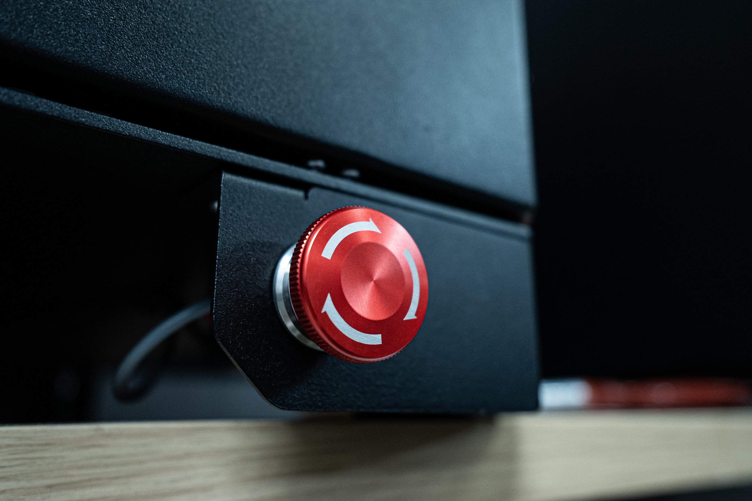 Close-up of a red, circular rotary knob on a black electronic device, with white arrows indicating rotation direction.