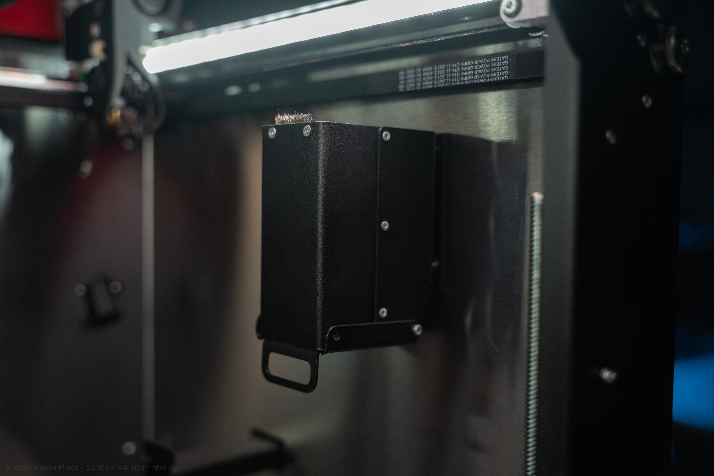 Close-up of a 3D printer's interior showing a black component attached to the metal frame with screws.