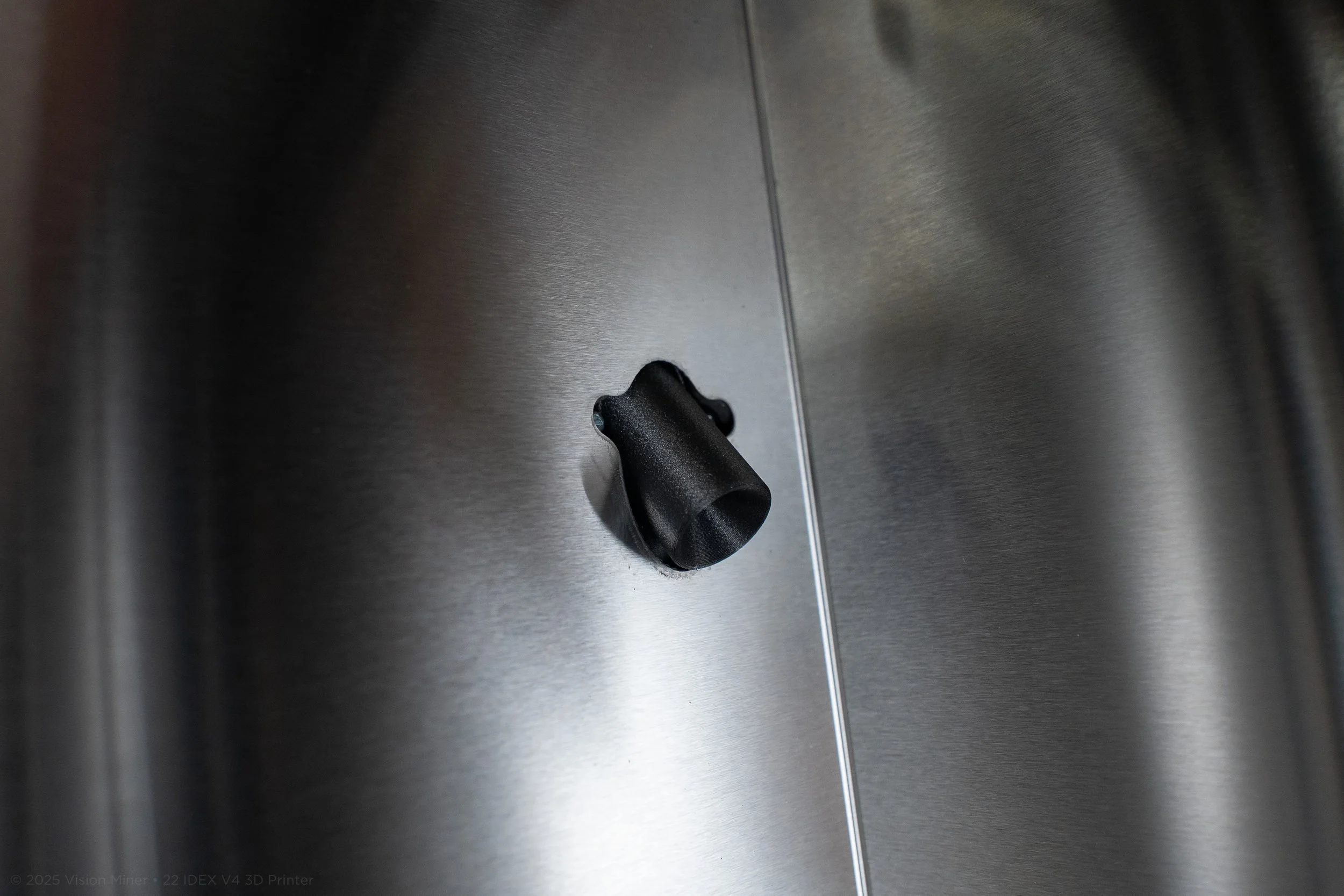 A close-up view of a black control knob on a stainless steel appliance, possibly an oven or refrigerator.