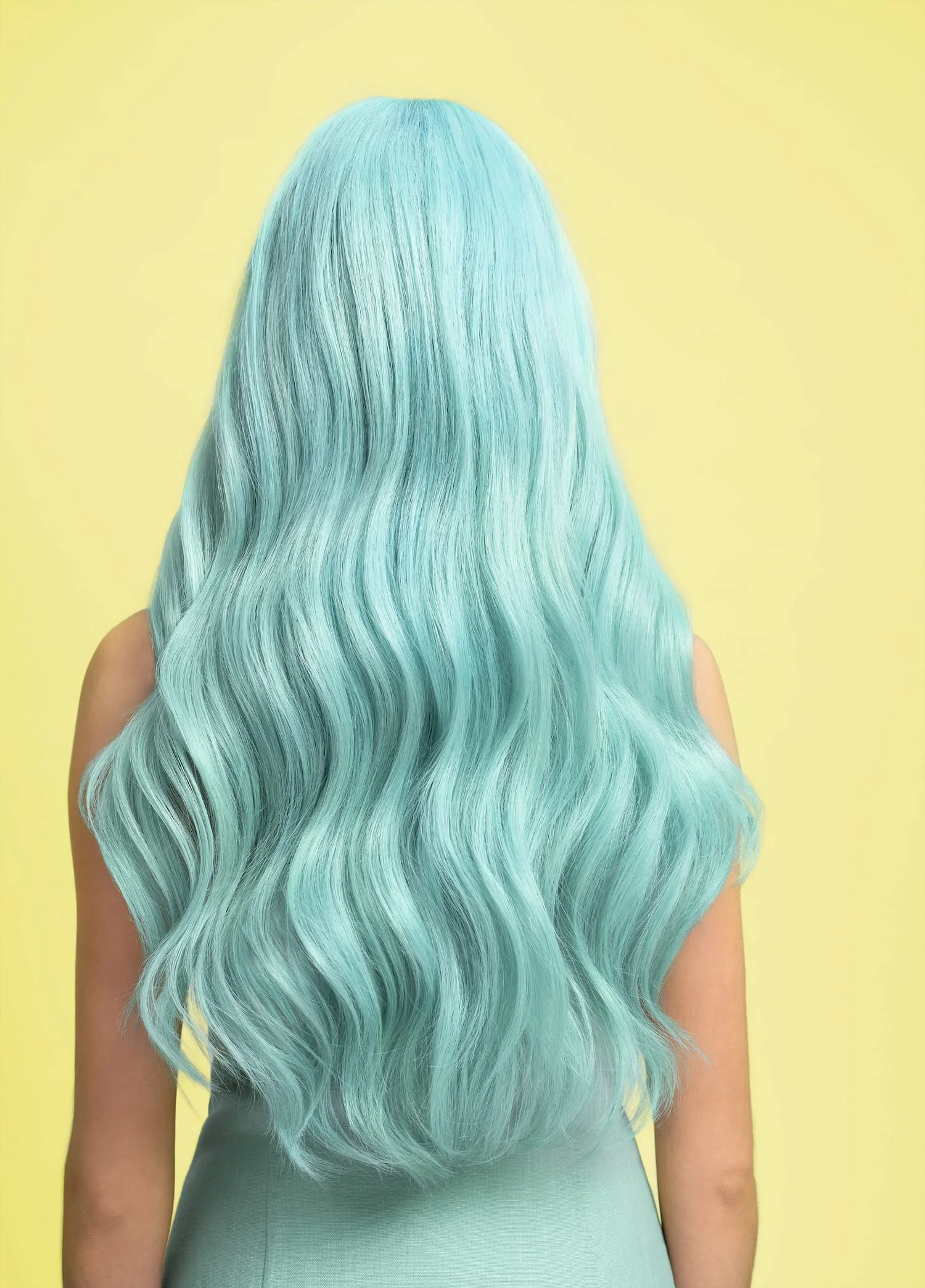 Back view of a person with long, wavy, bright blue hair against a yellow background.