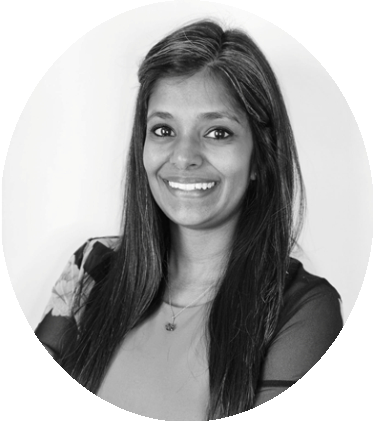 Black and white portrait of a smiling woman with long hair, wearing a top with sheer sleeves.