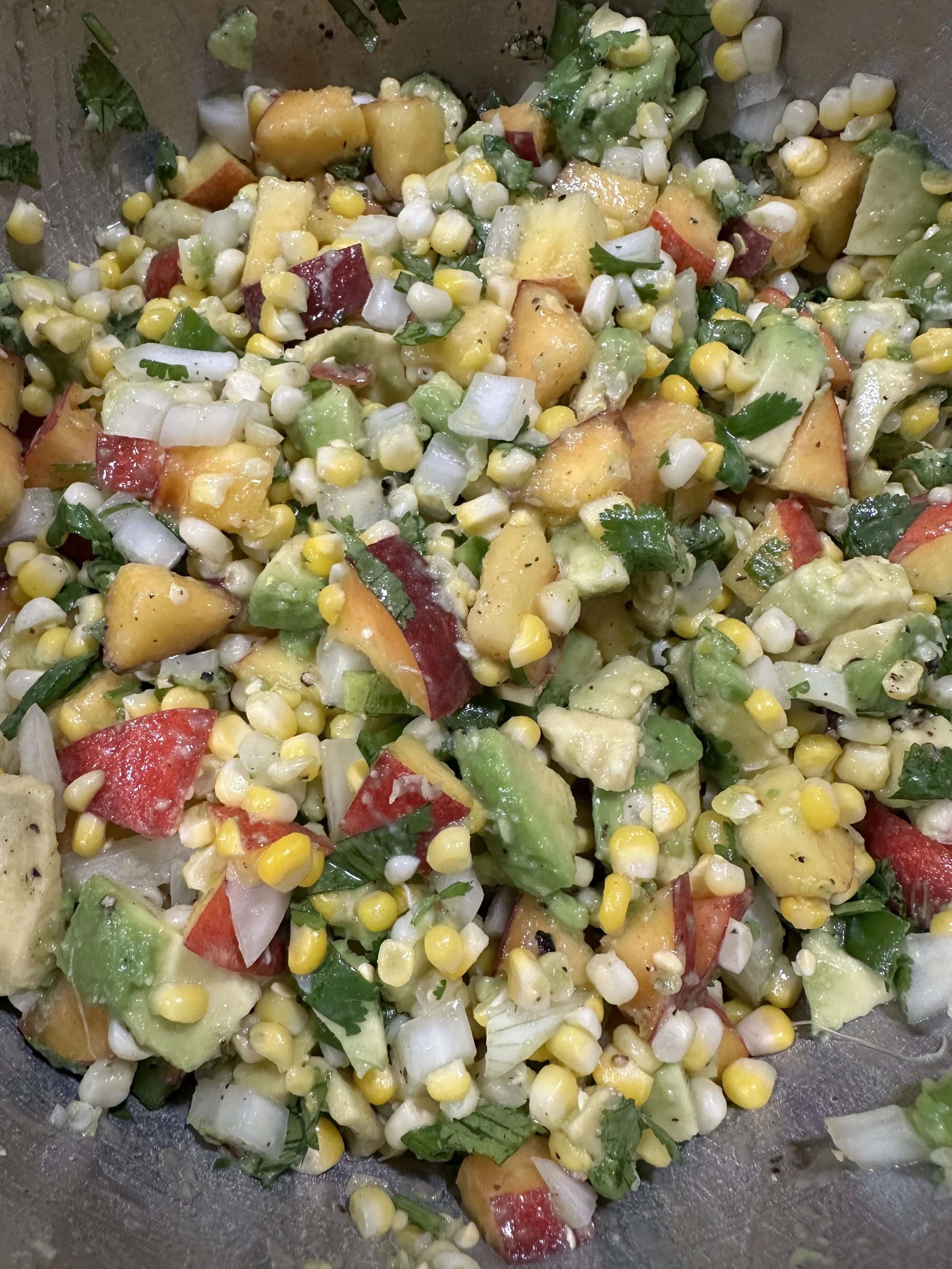 Mixed vegetable salad with corn, avocado, red bell peppers, onions, and cilantro.