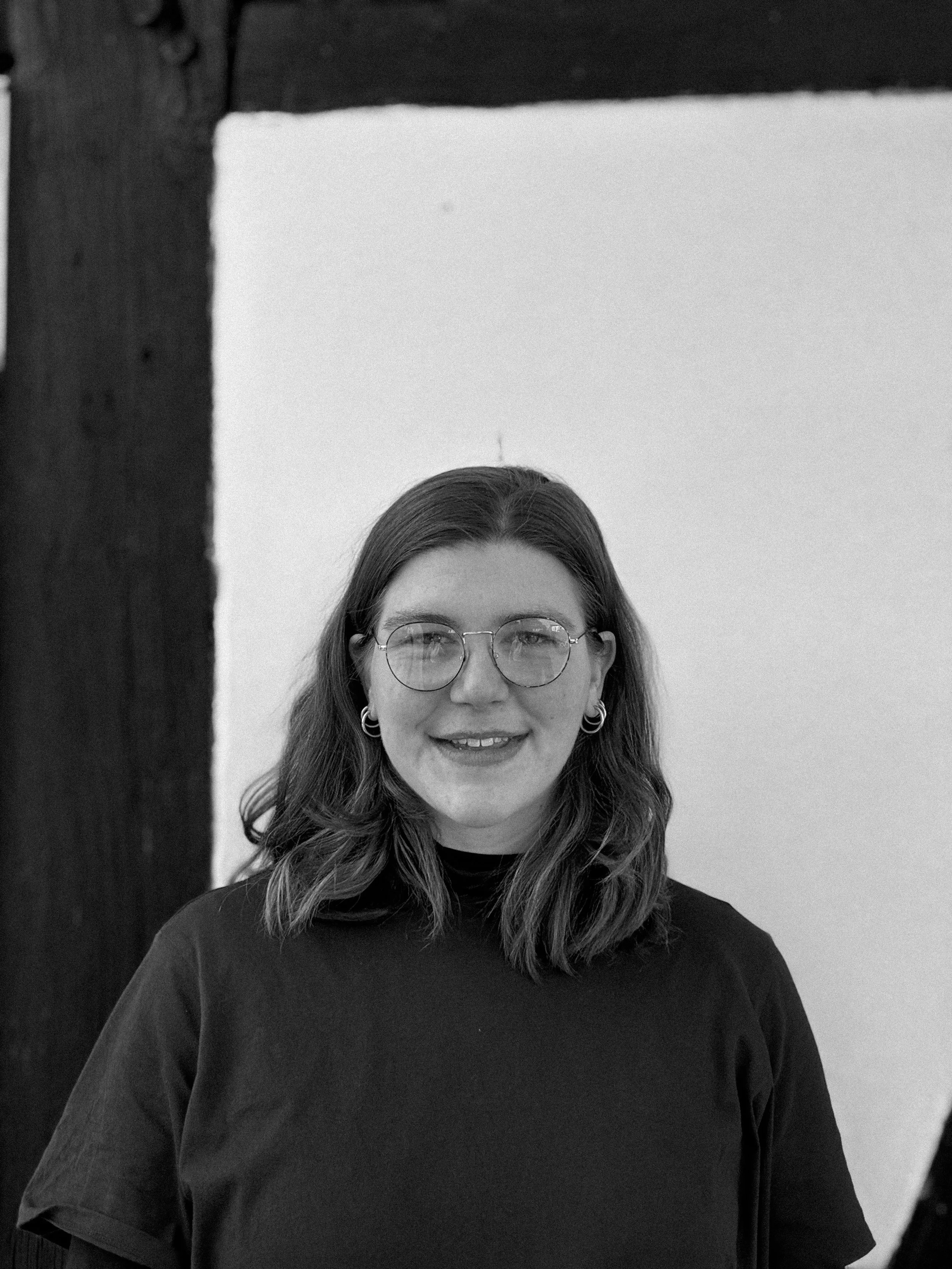 Eine Frau sitzt auf einer Schaukel im Garten, umgeben von grünen Bäumen und Sträuchern, bei schönem Wetter.