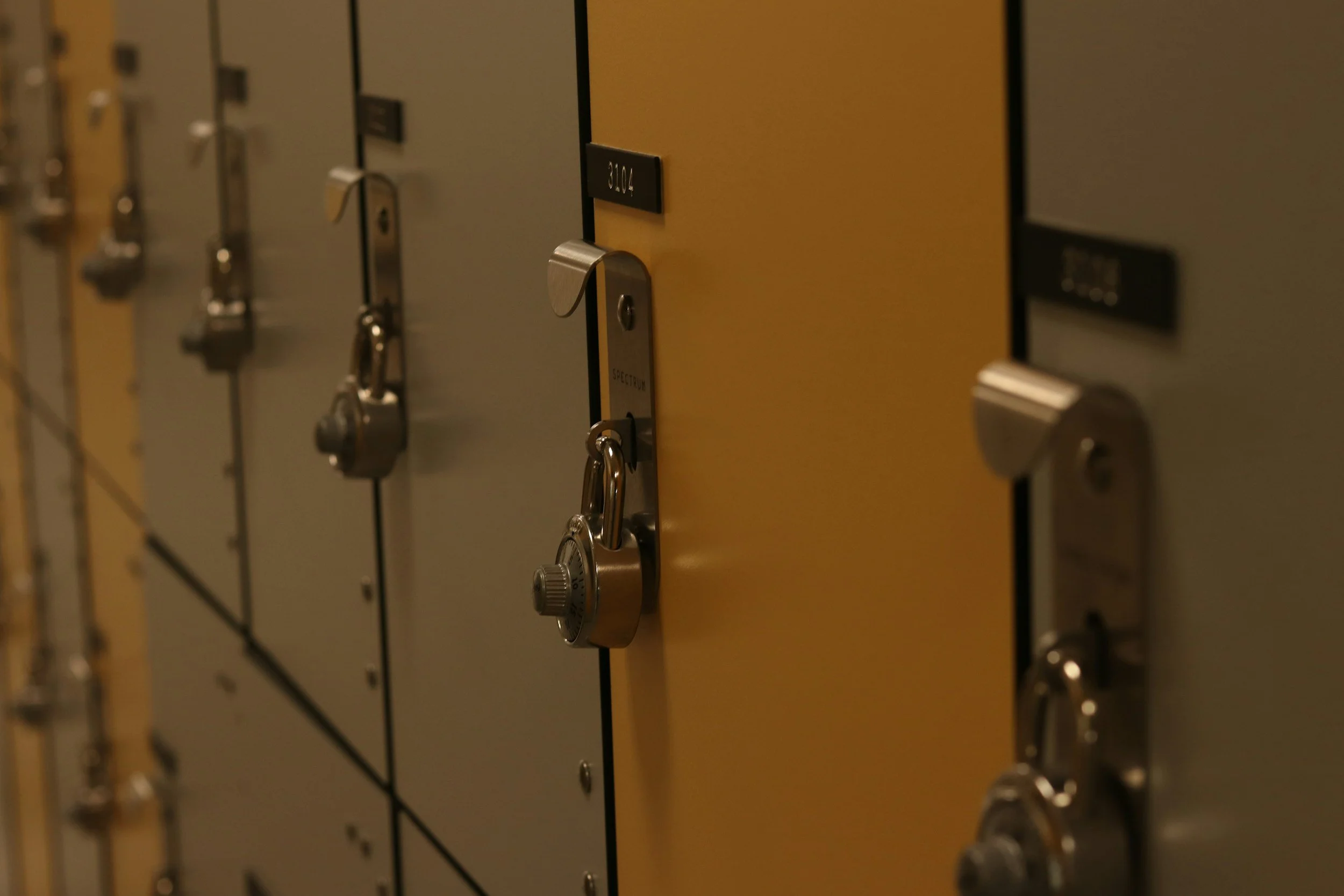 School lockers with combination locks, with one yellow locker in the middle.