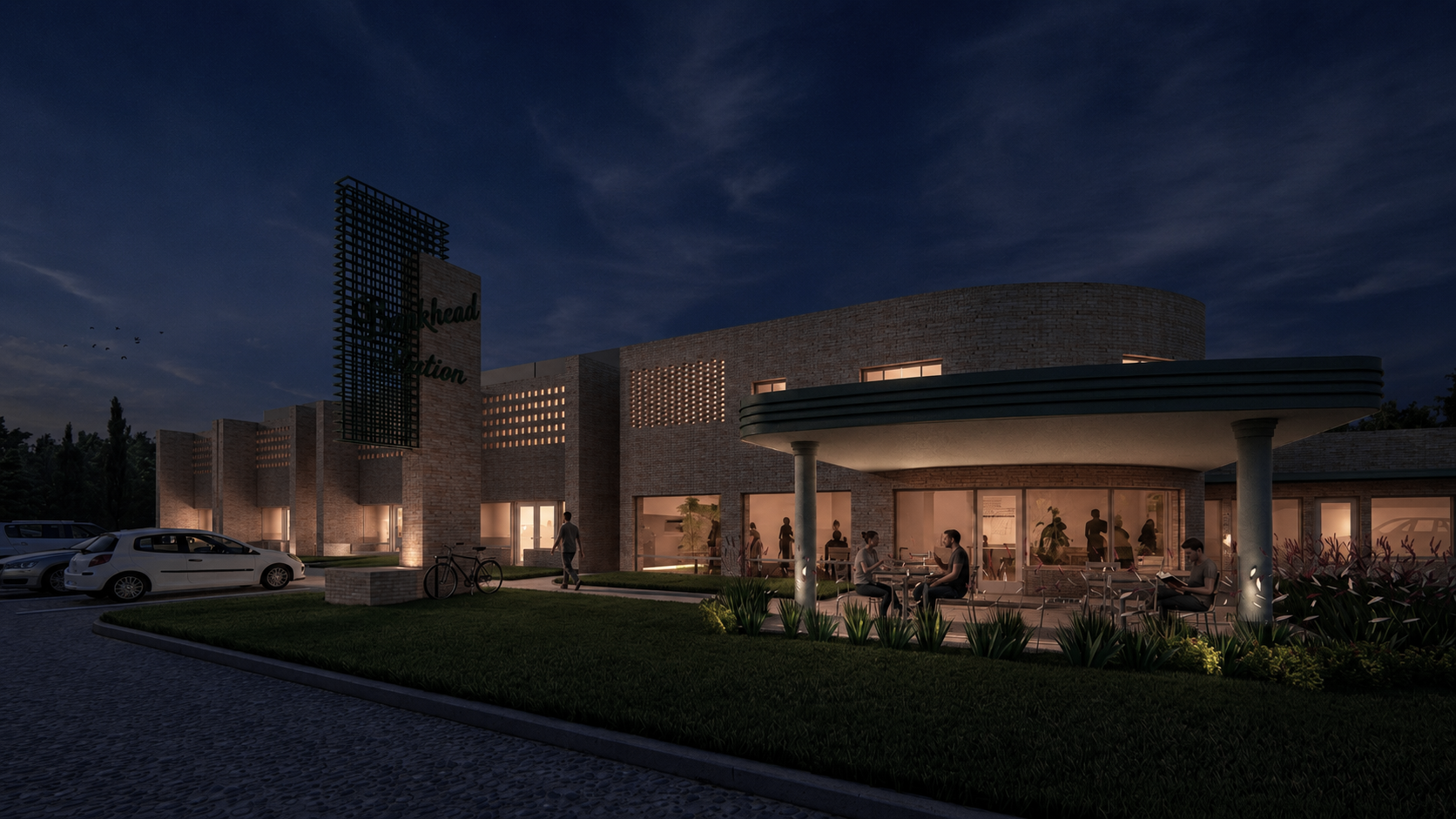 Exterior view of a modern brick building at night with illuminated indoor and outdoor seating areas, parked cars, bicycles, and a landscaped walkway.