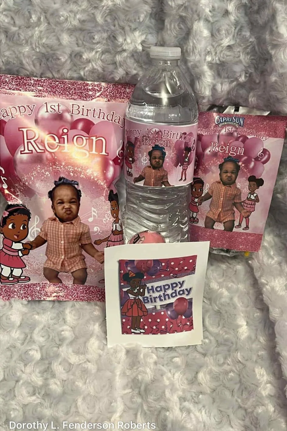 First birthday celebration for Reign with themed decorations, including a water bottle, birthday cards, and a small card, all with images of a young girl and pink balloons.