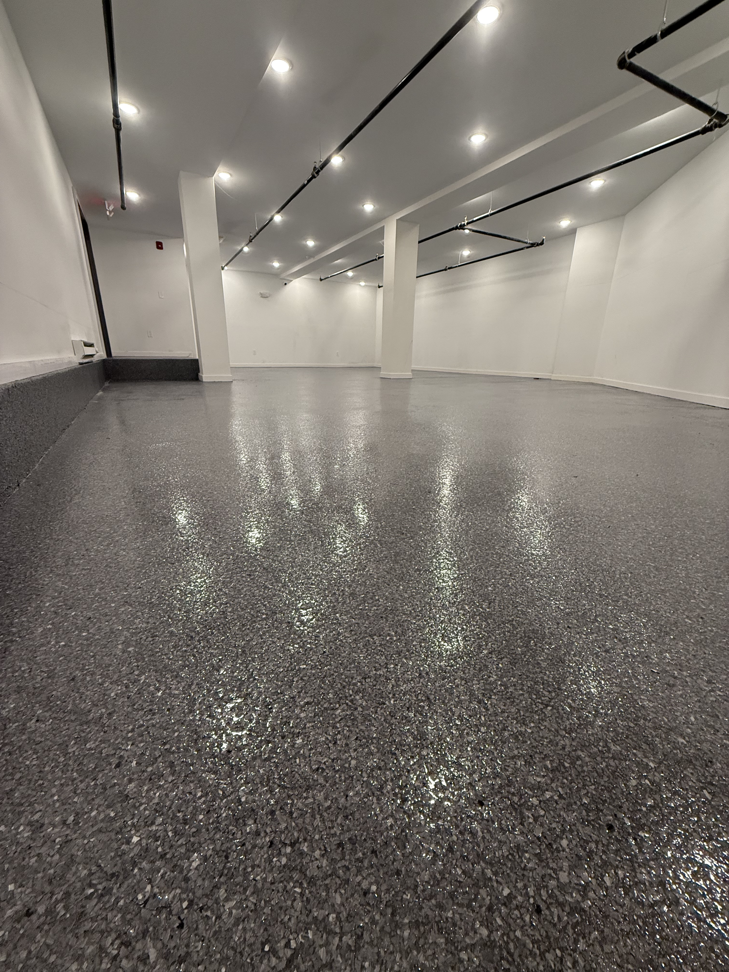 Polymer flake garage floor with polyaspartic topcoat