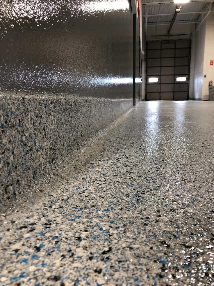 Integral resin cove base at a floor-to-wall transition