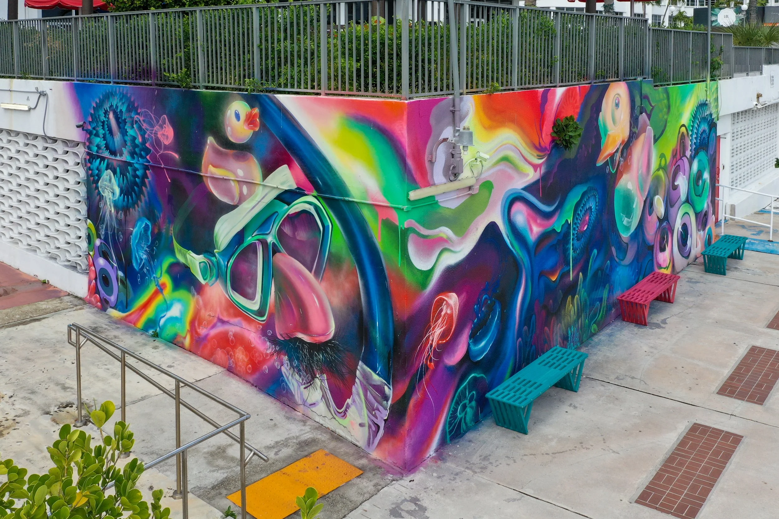 Colorful mural featuring a pair of sunglasses, a rubber duck, and abstract swirling patterns on an exterior wall at Vice City marine by Hiero Veiga, HoxxoH and Suarez