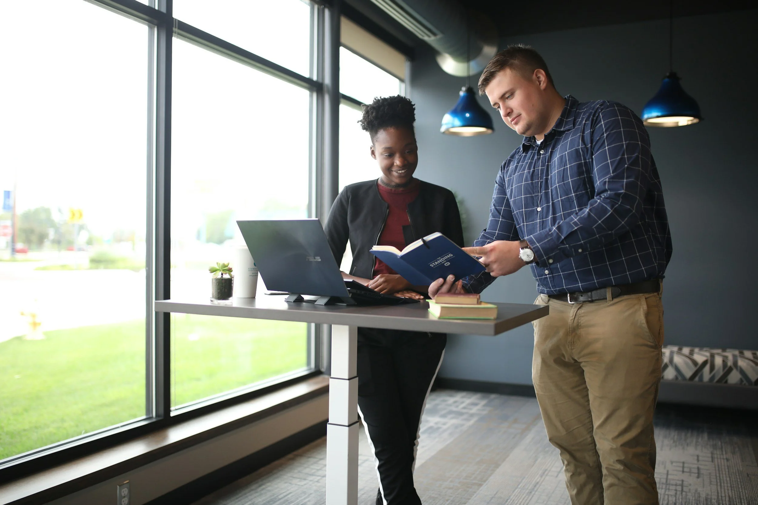 Woman collaborating with male while standing at desk with computer
