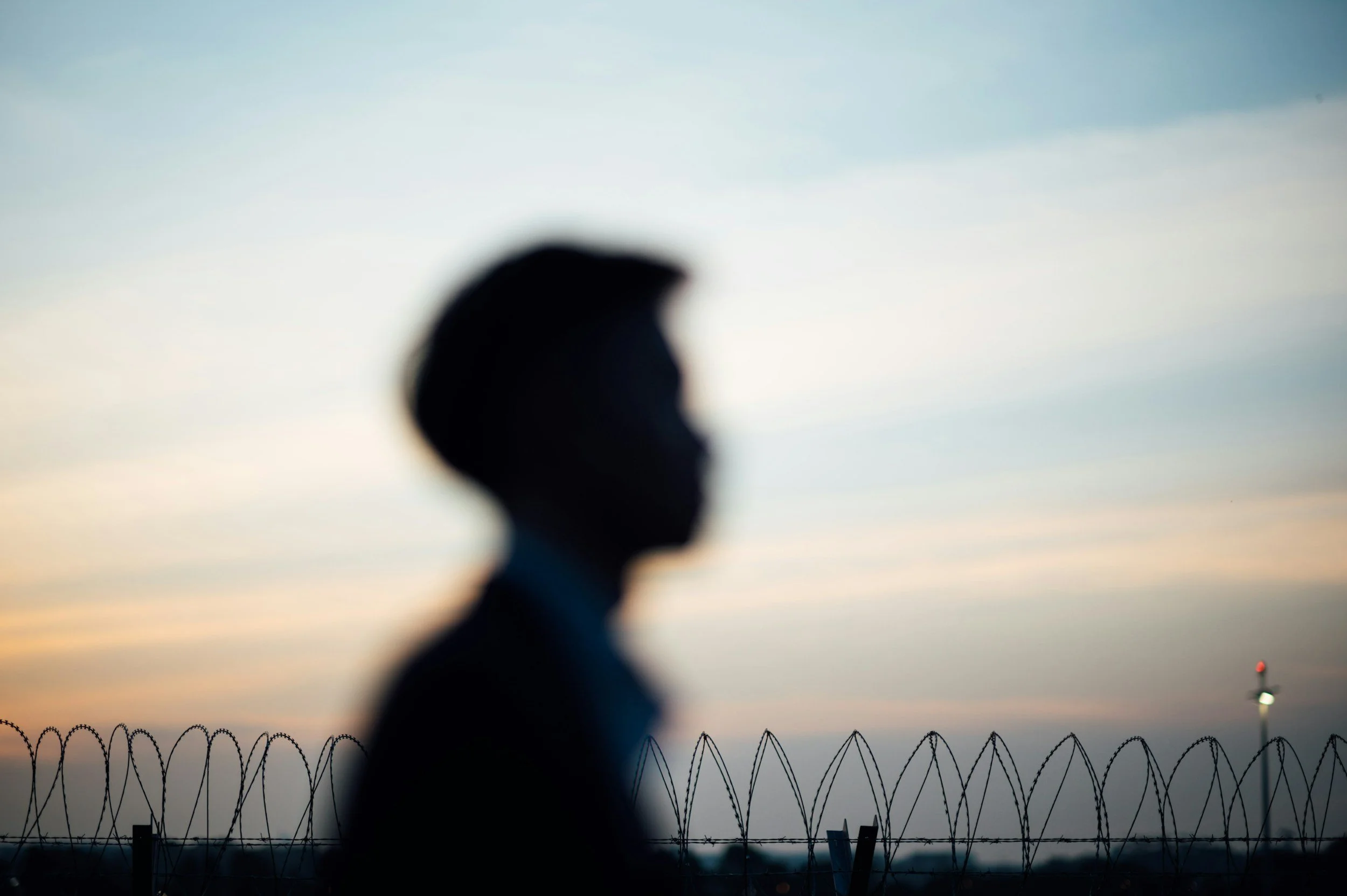 Silhouette of individual behind razor wire