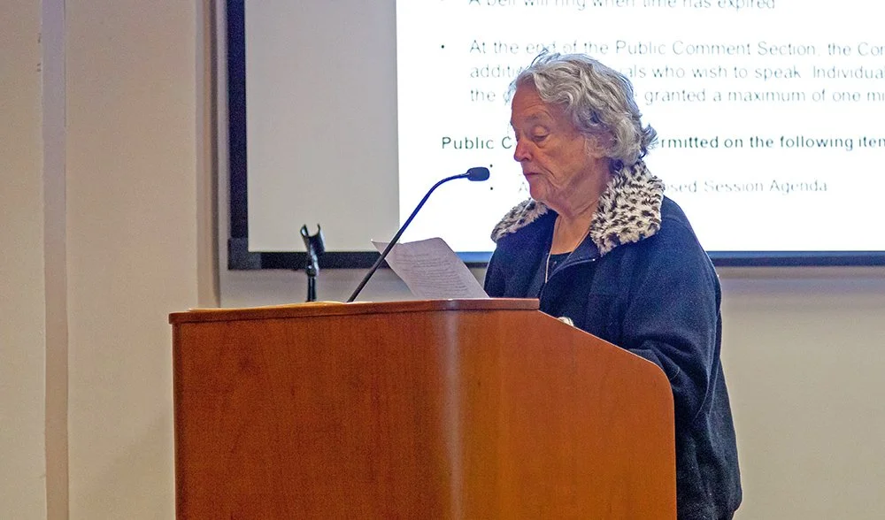 A woman speaking into a microphone at a podium.