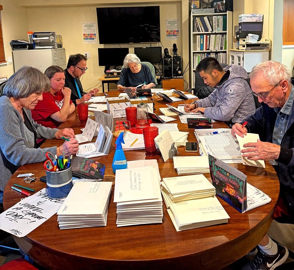 A group of volunteers around a table working on a mailout session.