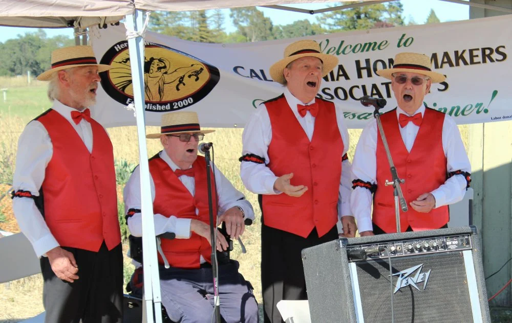 A barbershop quartet sings at CHA's anniversary dinner. They are dressed in classic white and red with red bow-ties and matching hats.