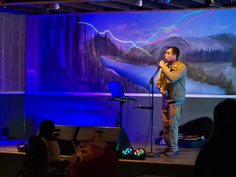 A Latino man at the microphone on stage at an event.
