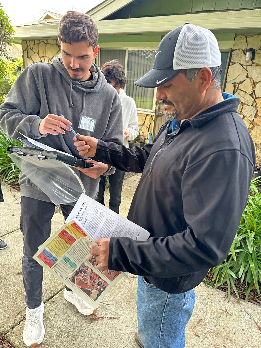 A volunteer passes a pen to a new member who is signing up.