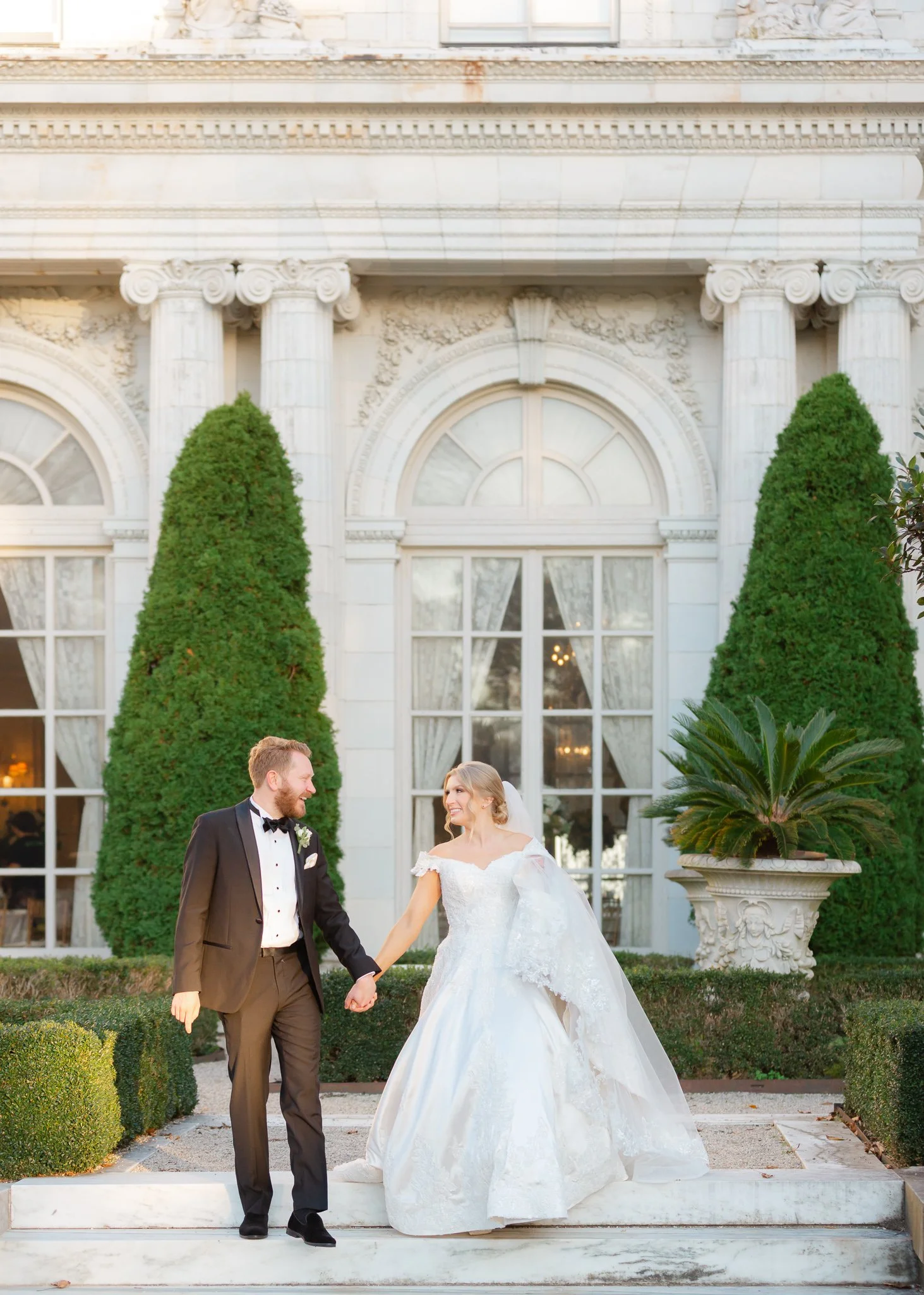 Bride and groom holding hands outside Rosecliff Mansion in Newport Rhode Island on their wedding day