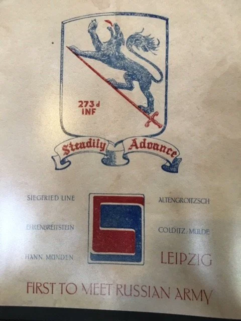 A badge with a lion holding a spear, the number 273d INF, a banner with the words 'Staddily' and 'Advance,' a logo with a red and blue square, and text that mentions Leipzig and the Russian Army.