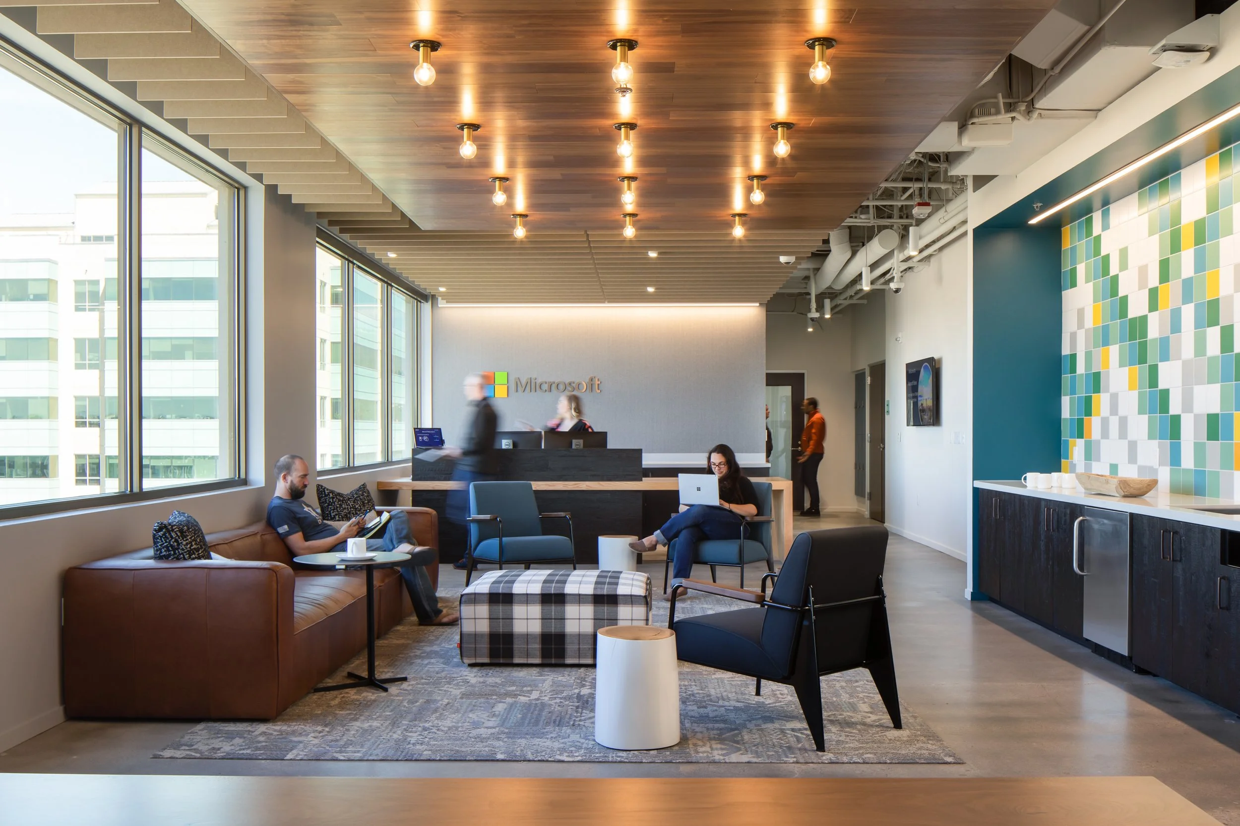 Modern Microsoft office reception area with seating, a reception desk, and large windows with city view.