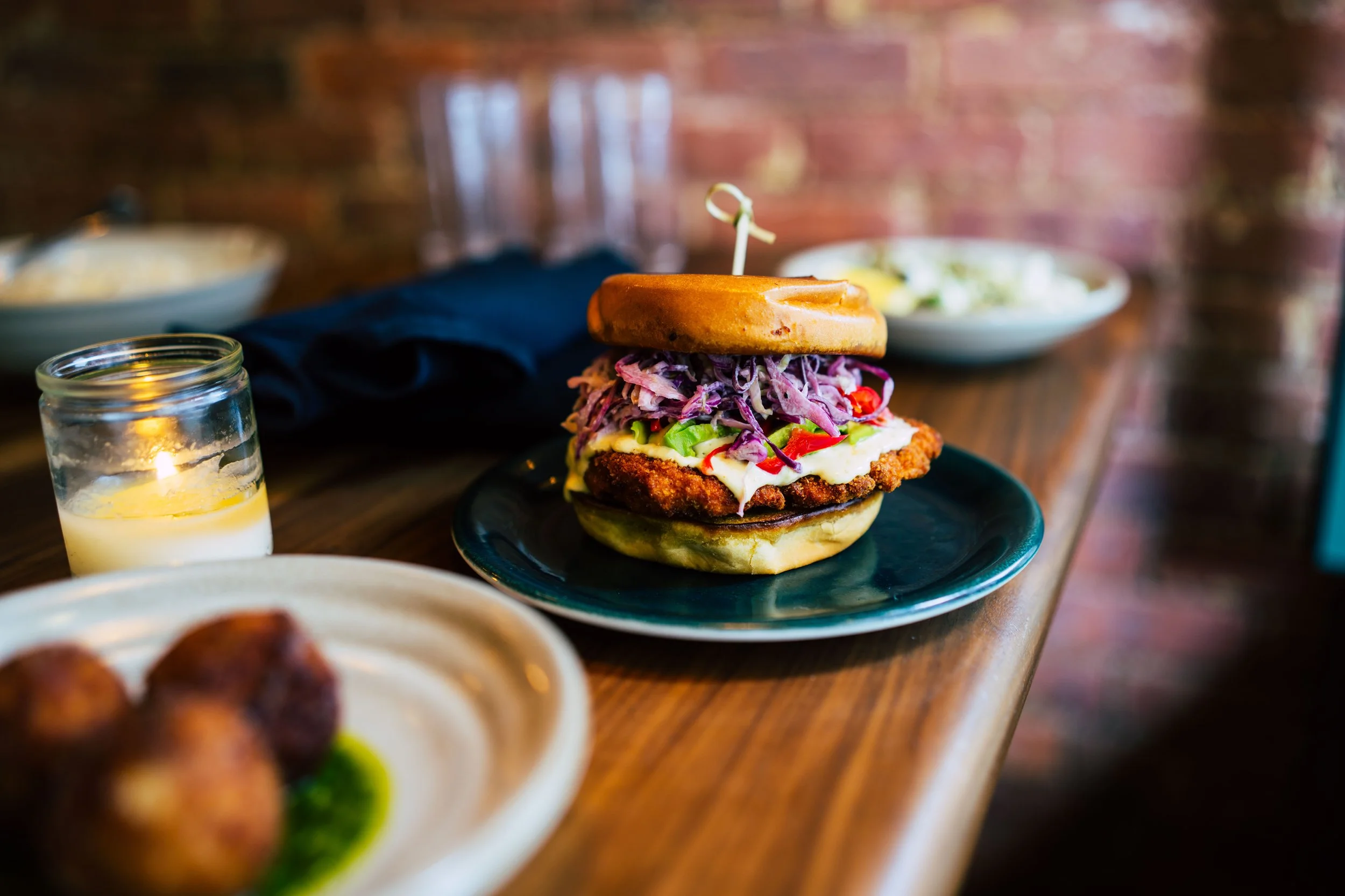 Close-up of a sandwich on a black plate, on a wooden table.
