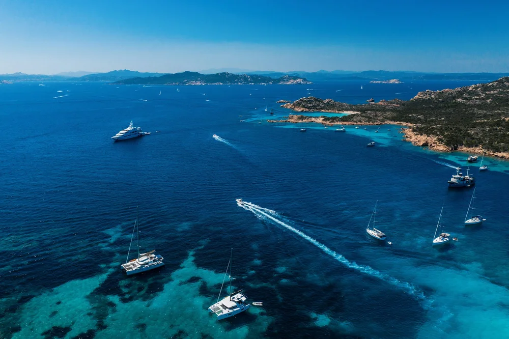 Boats and rocky islands along the Sardinian coastline, seen from above.