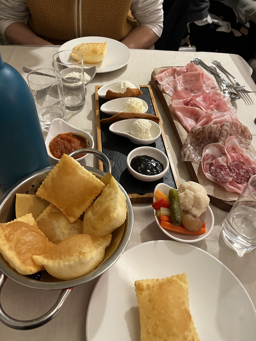 Gnocco fritto, local salumi and accompaniments on a shared table in Emilia-Romagna.