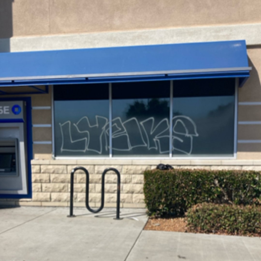 "Technician applying clear anti-graffiti film to a commercial storefront window to protect against vandalism and surface damage"