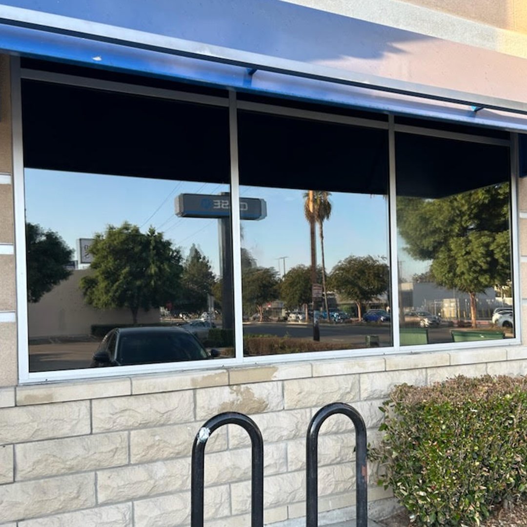 "Technician applying clear anti-graffiti film to a commercial storefront window to protect against vandalism and surface damage"