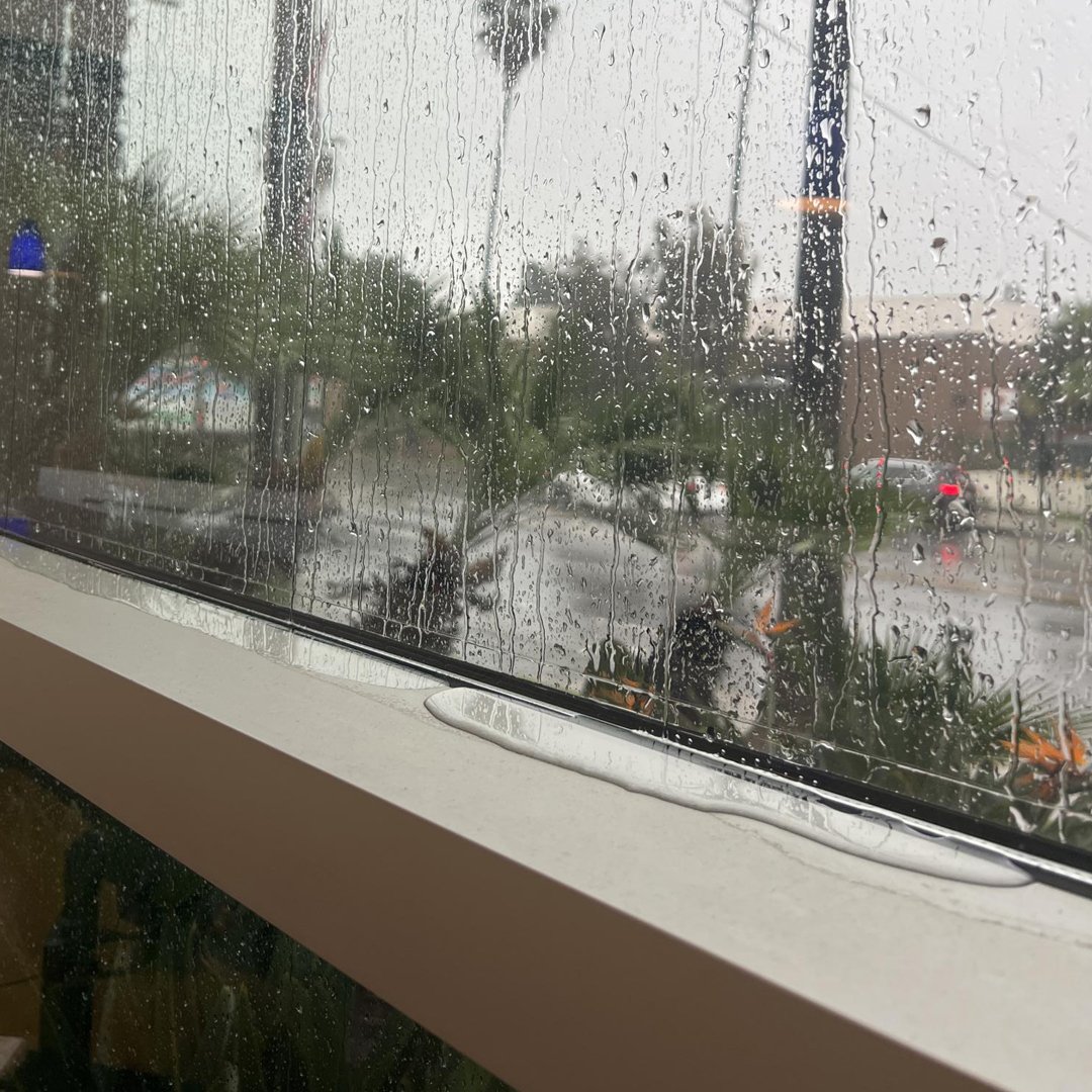 "PH Glass technician sealing window edges with waterproofing materials to prevent water intrusion in a commercial building"