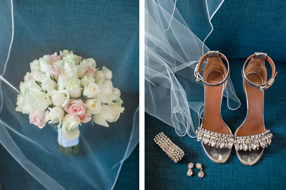 A bridal bouquet of white and light pink roses, and a pair of silver Givenchy high-heeled sandals with rhinestone embellishments, along with rhinestone jewelry, all placed on a turquoise fabric surface.