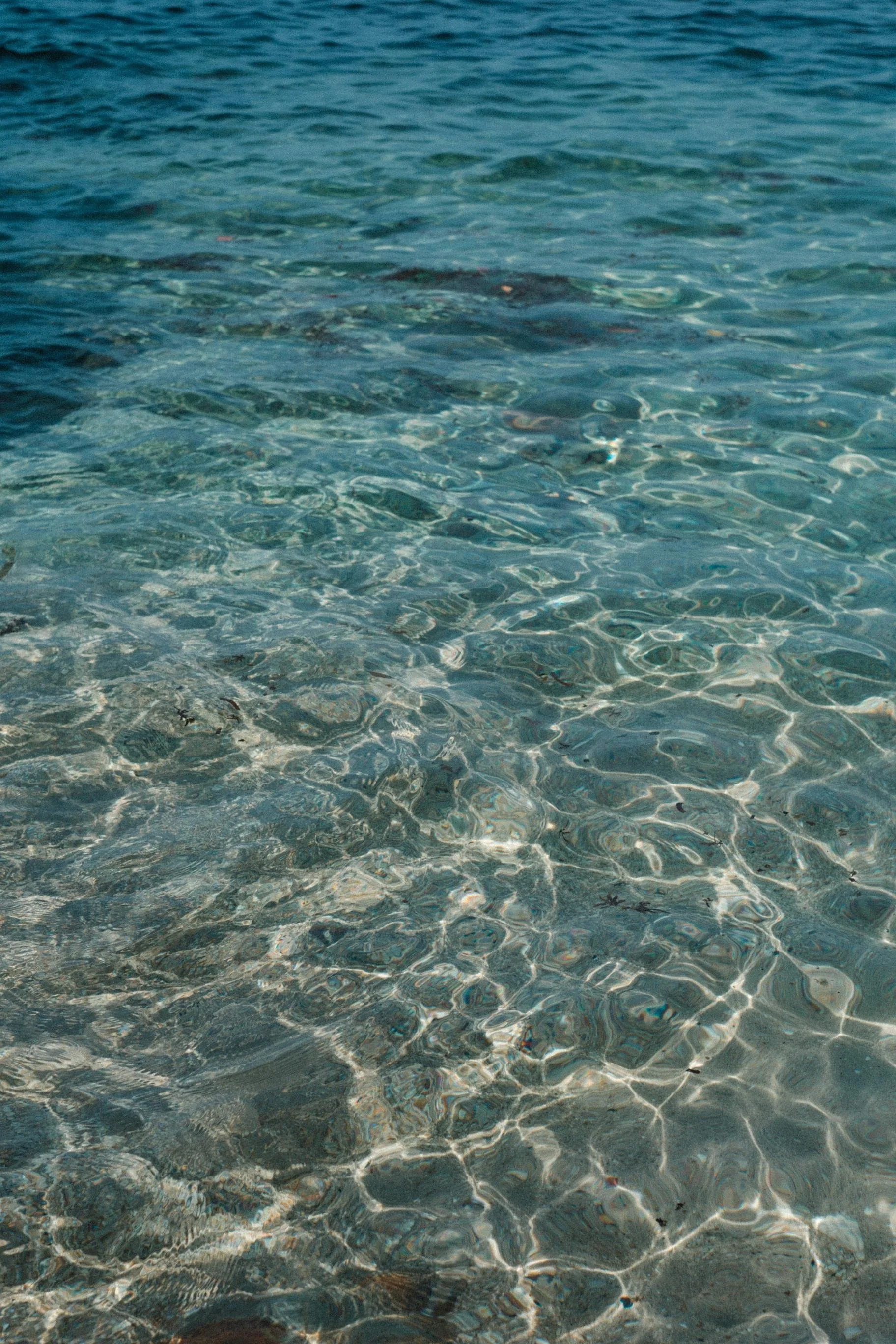 Clear blue ocean water with sunlight reflecting on the surface.
