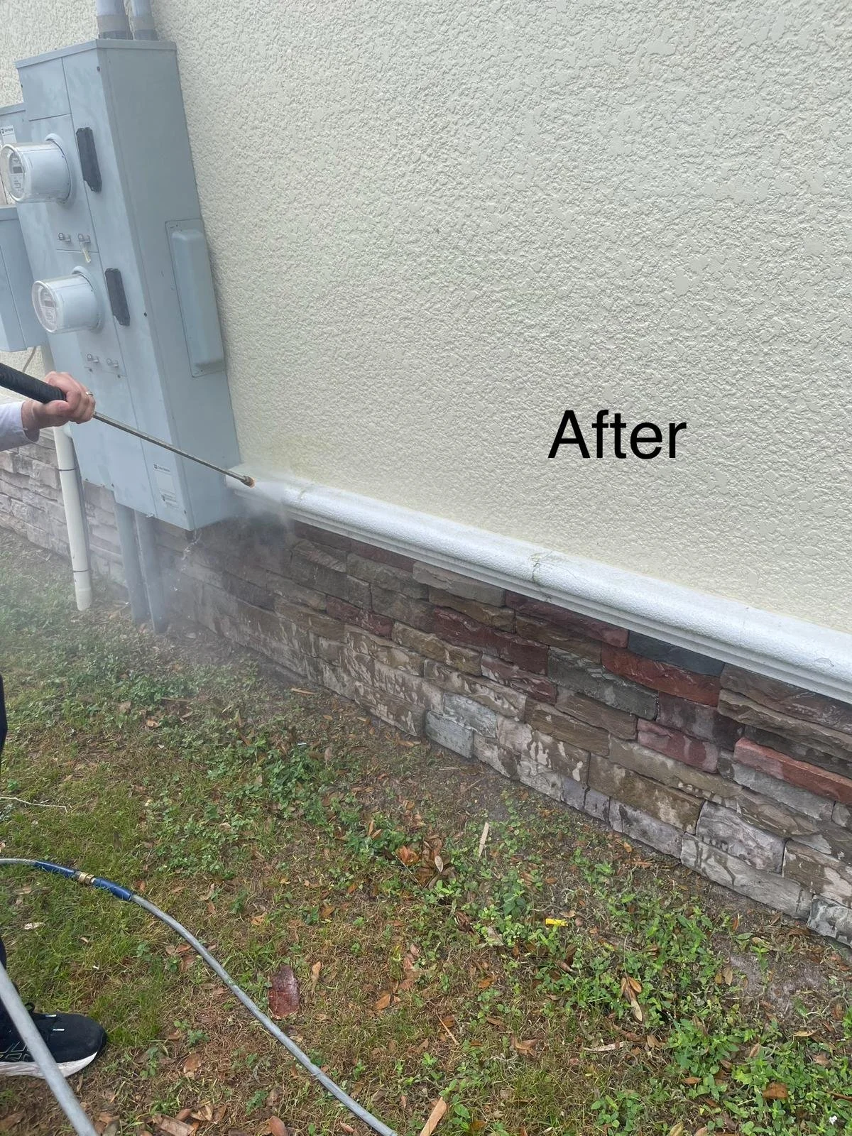 Person power washing the exterior wall of a house, showing a clean section labeled 'After' with a textured yellow wall and a brick foundation.